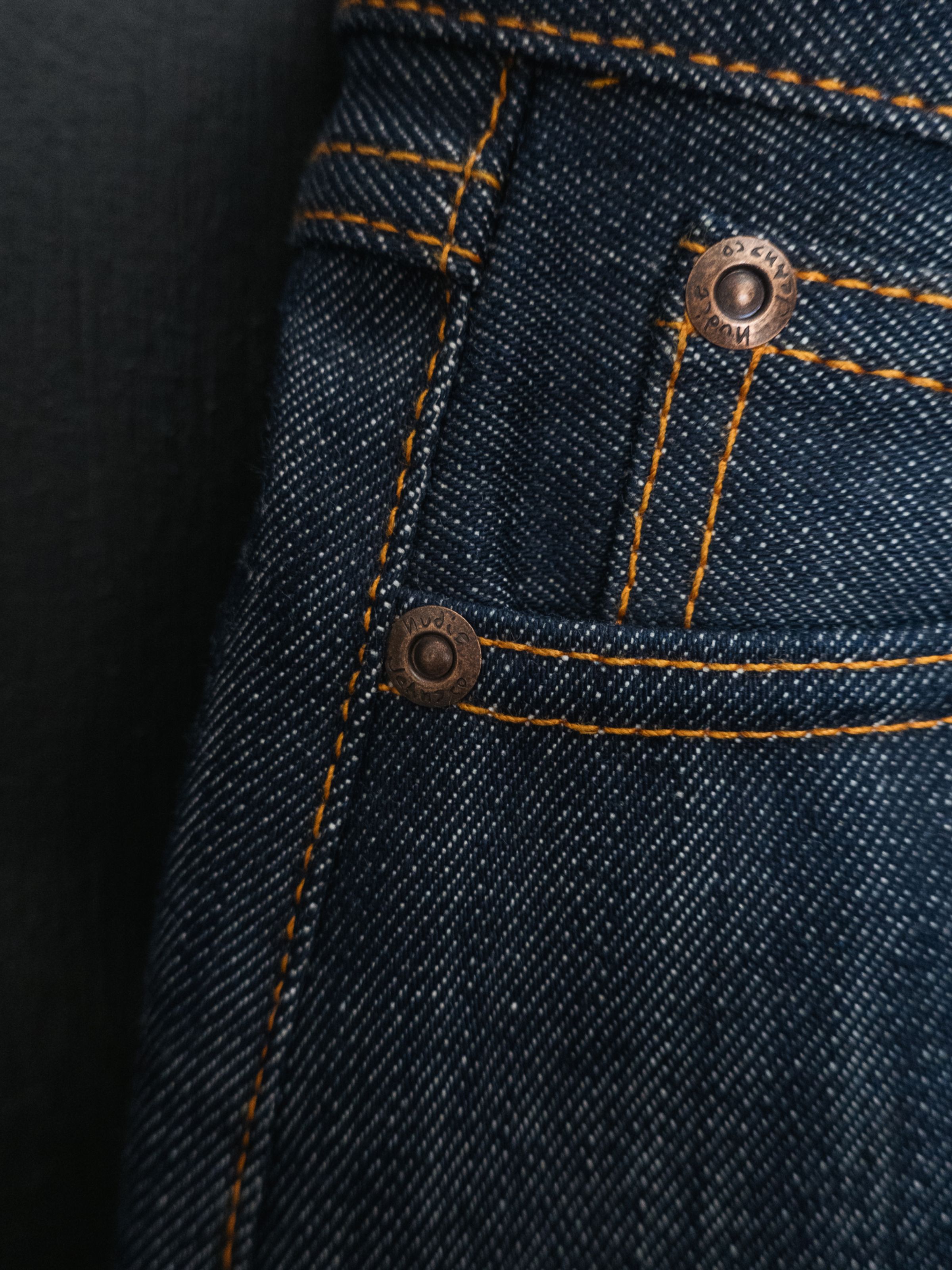 Nudie Jeans Wide Heidi Dry Sunburns, women's wide-leg jeans, showing a close-up of the copper rivets and orange stitching.