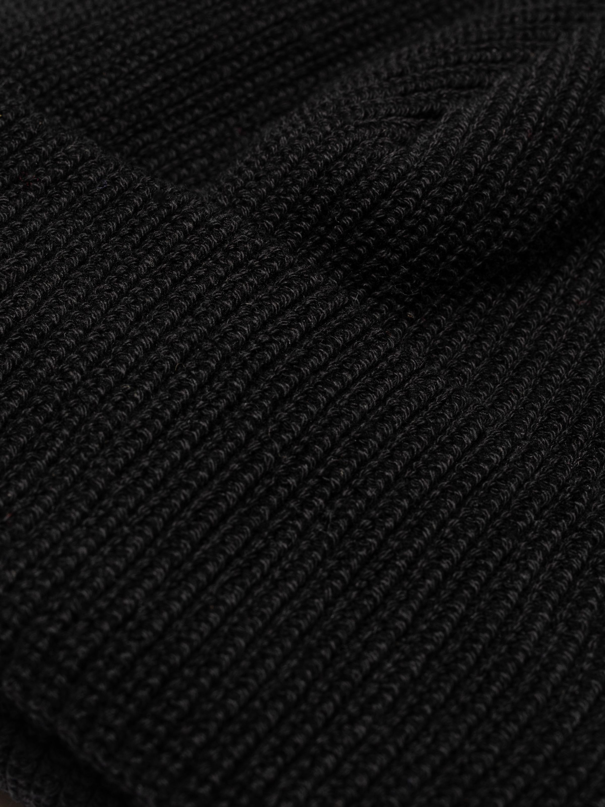 Nudie Jeans Cotton Beanie in black, a close-up of the ribbed organic cotton knit.