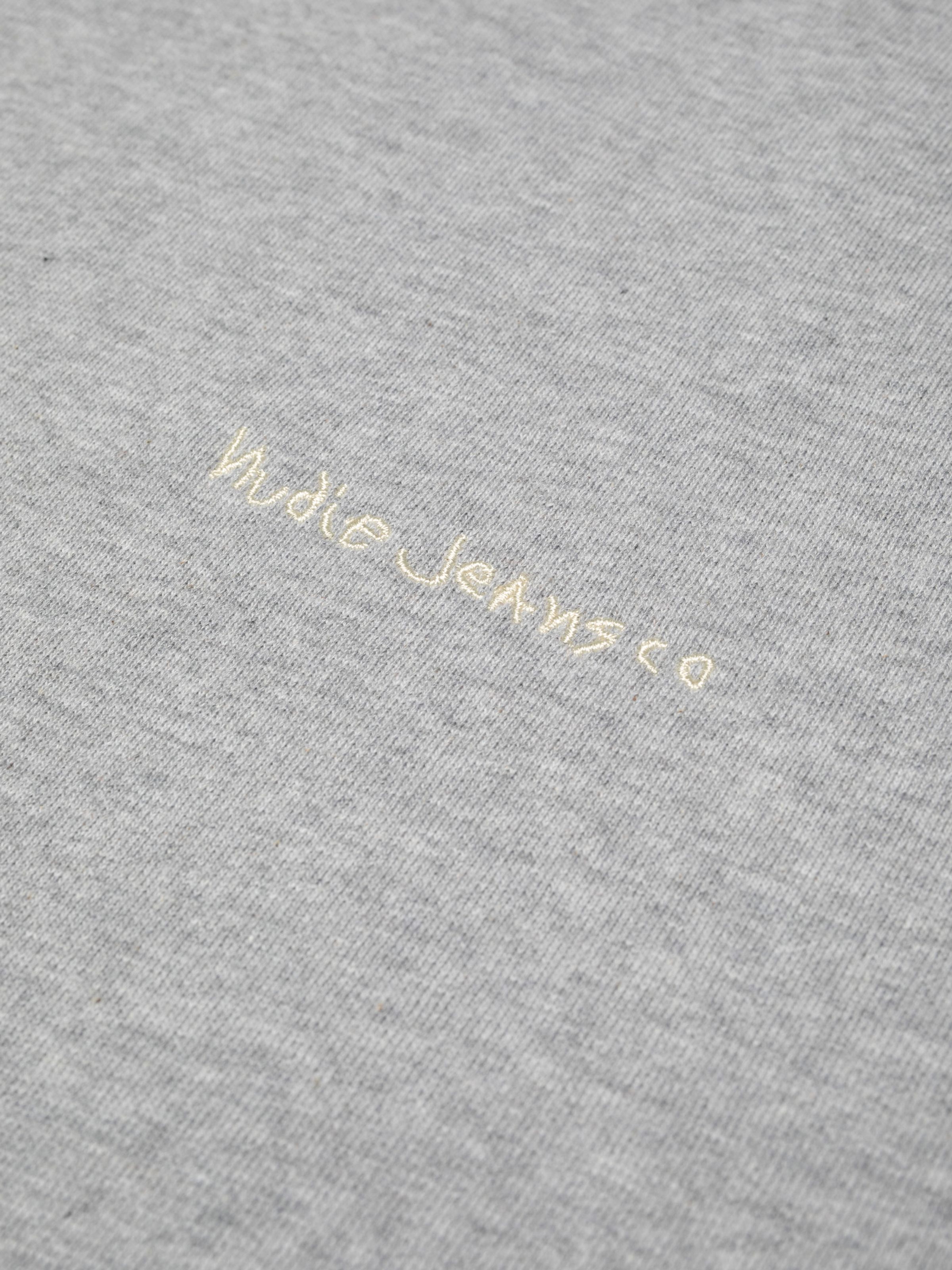 Nudie Jeans Gunde Logo Hoodie in Greymelange, close-up shot of the embroidered logo on the chest.
