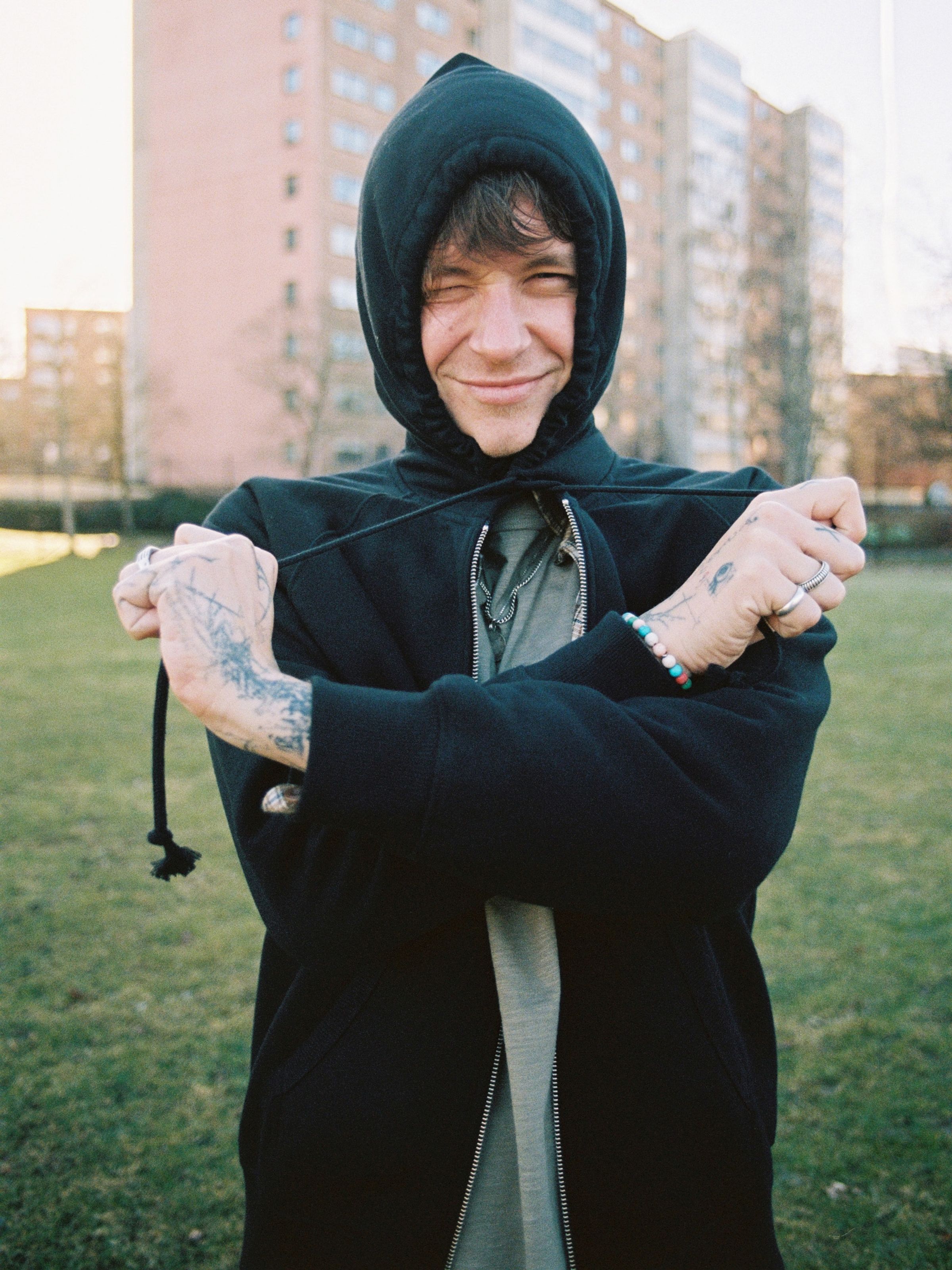 Nudie Jeans Gunde Logo Zip Hoodie in Black, a men's zip hoodie worn by a model outdoors.