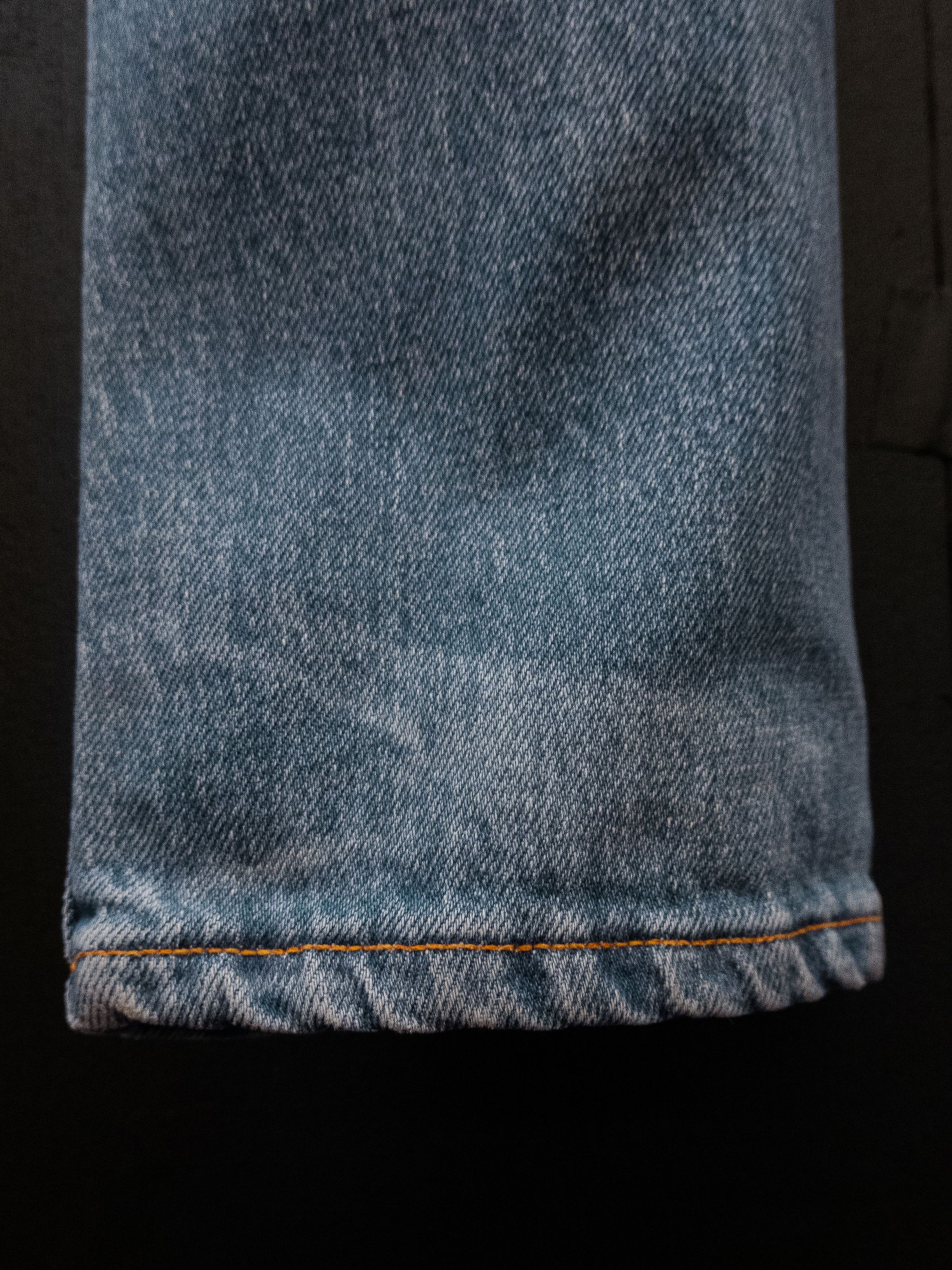 Nudie Jeans Lean Dean Hidden Tracks, close-up of the hem highlighting the orange stitching and light blue wash.