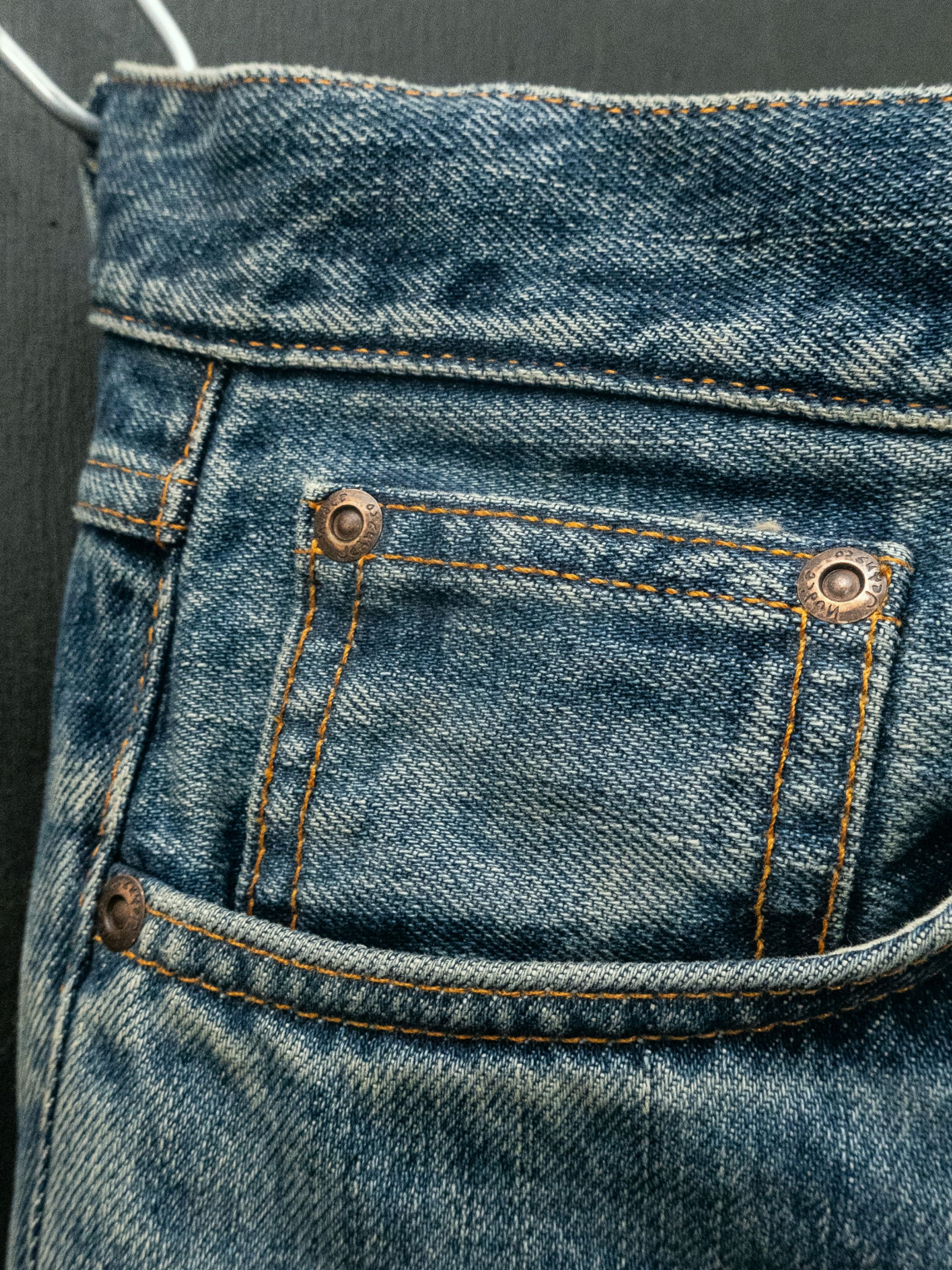 Nudie Jeans Gritty Jackson Thriller Tracks, close-up of the front pocket showing washed denim and copper rivets.