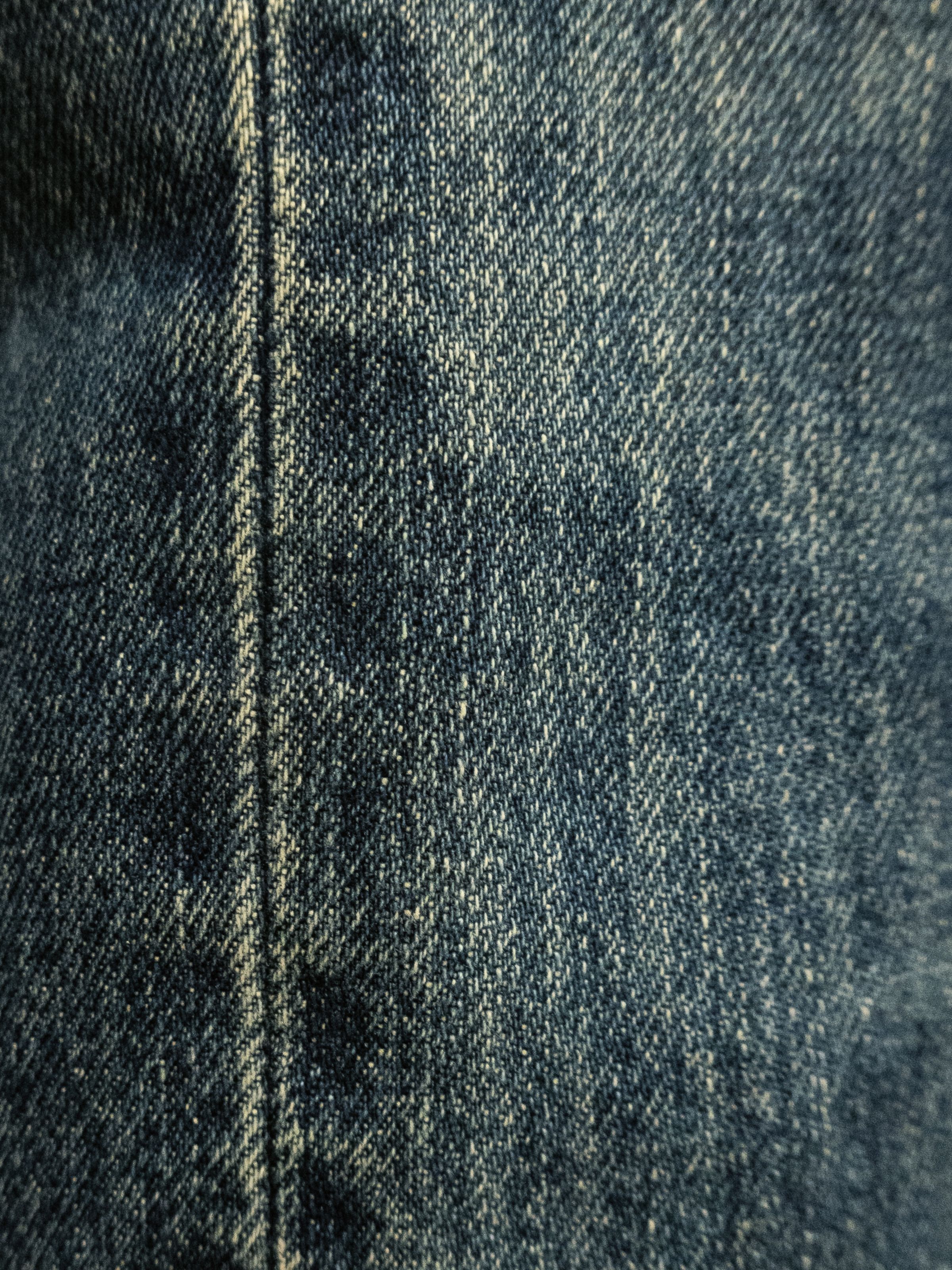 Nudie Jeans Gritty Jackson Thriller Tracks, a close-up detail shot of the mid-blue rigid denim fabric and seam.