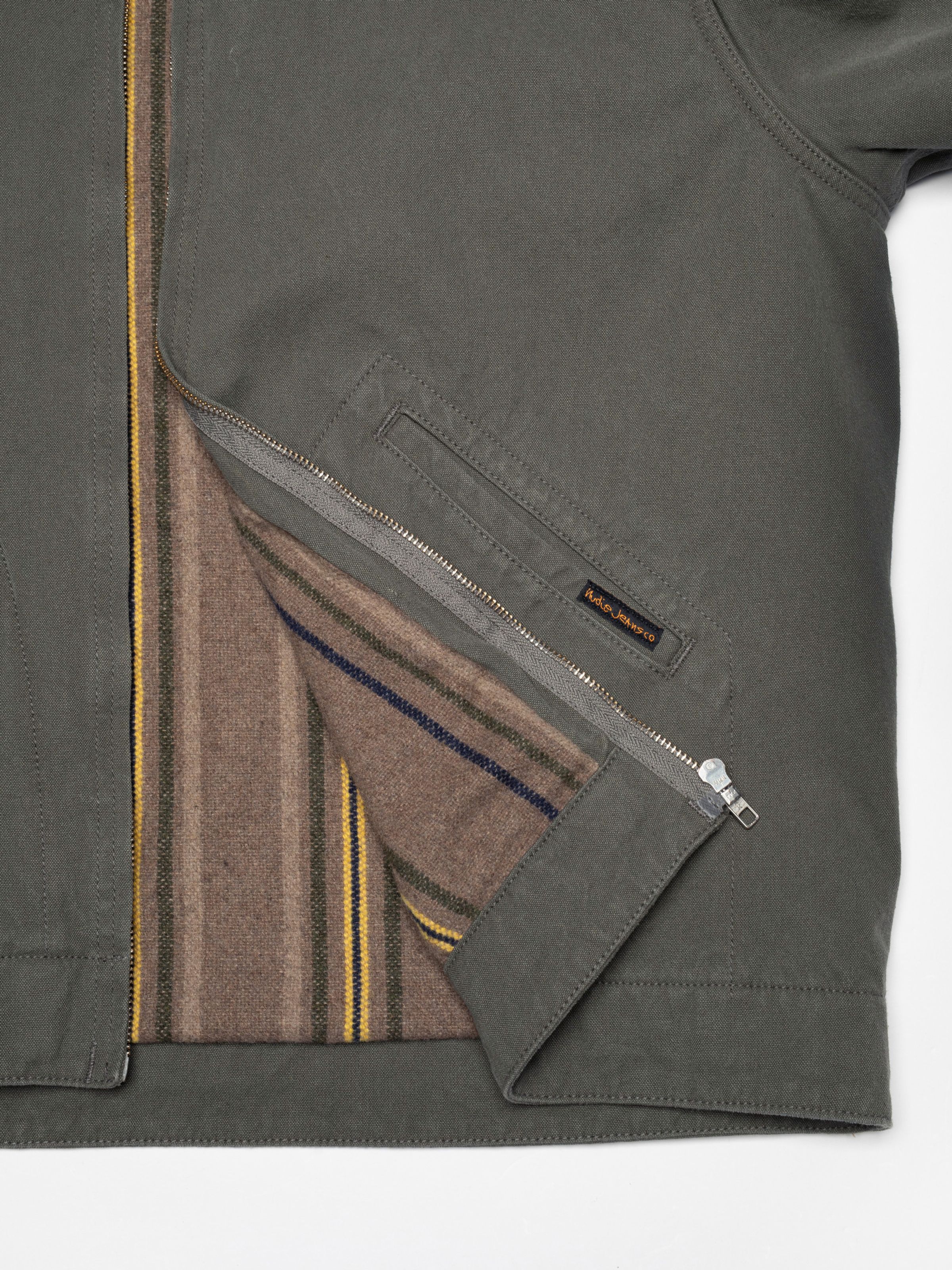 Nudie Jeans Blake Zip Jacket Duck Canvas Green, close-up showing the striped wool-mix blanket lining and inner pocket.