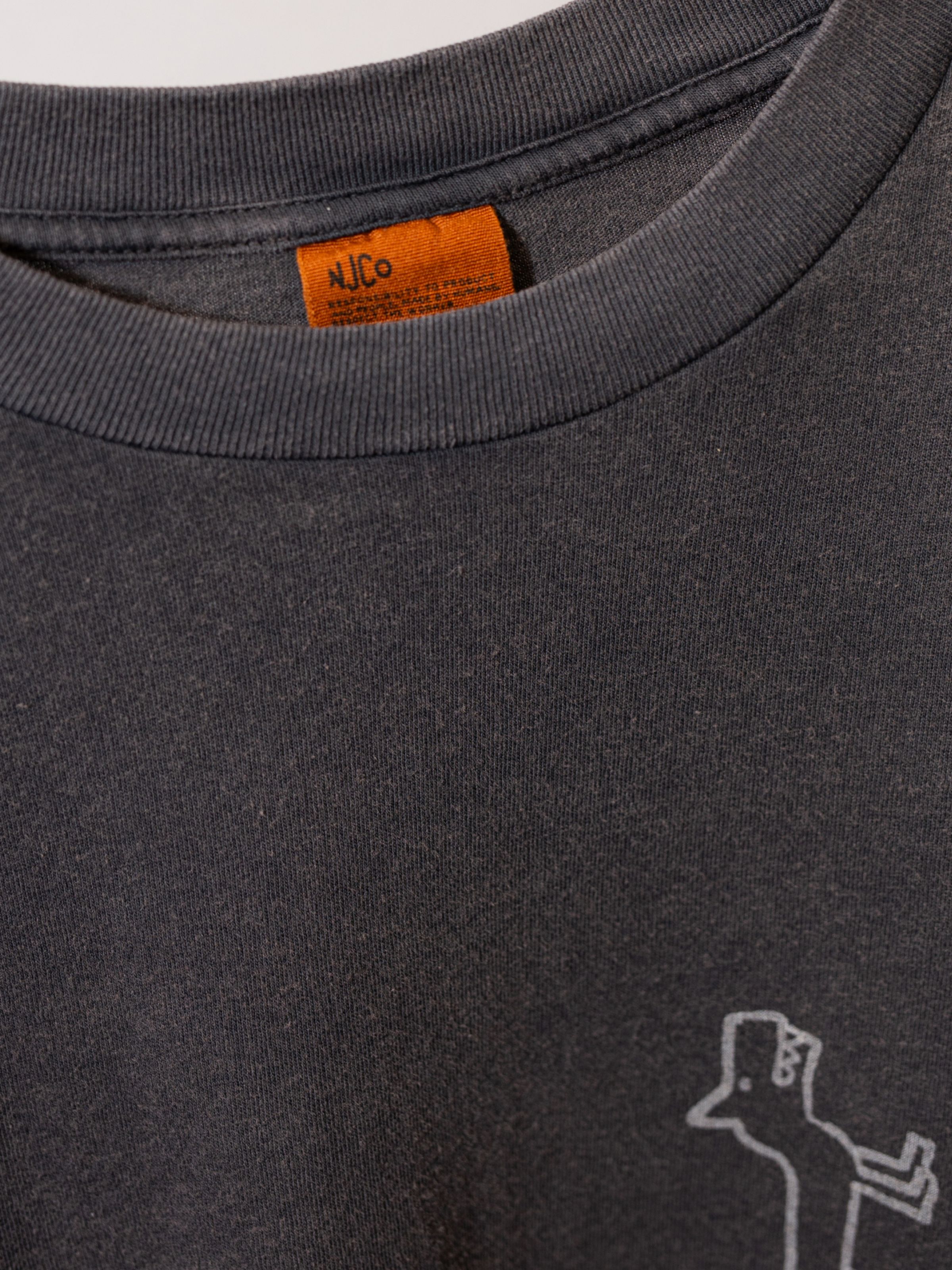 Nudie Jeans Koffe Scratched Tracks T-Shirt in Antracite, a men's t-shirt showing a close-up of the neckline and brand tag.