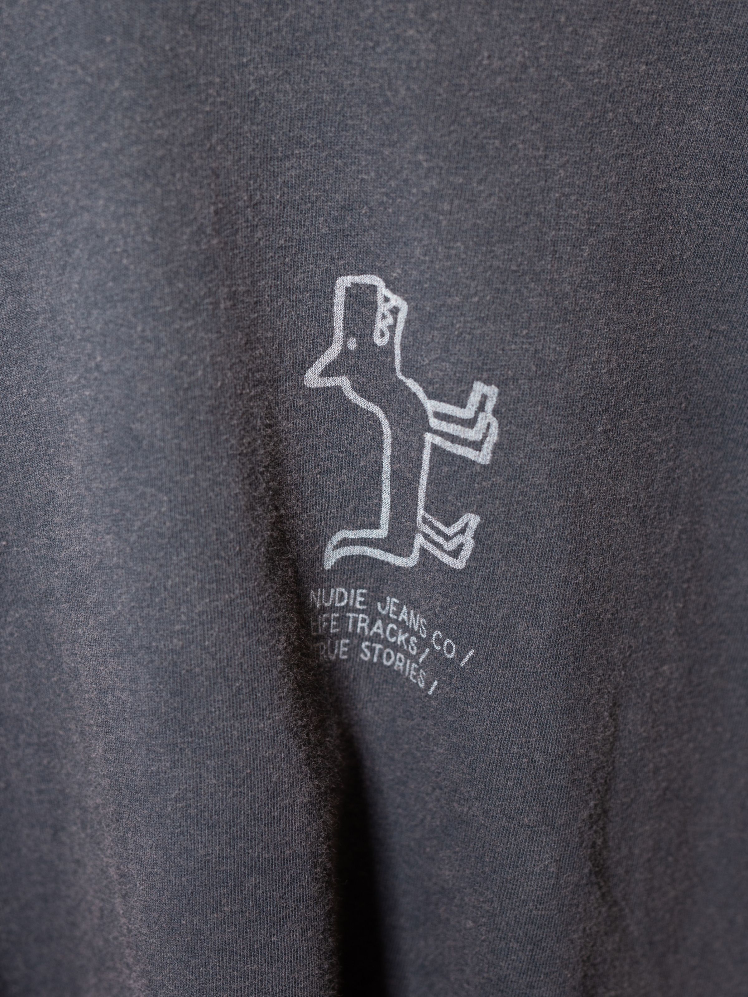 Nudie Jeans Koffe Scratched Tracks T-Shirt in Antracite, showing a close-up of the chest print detail.