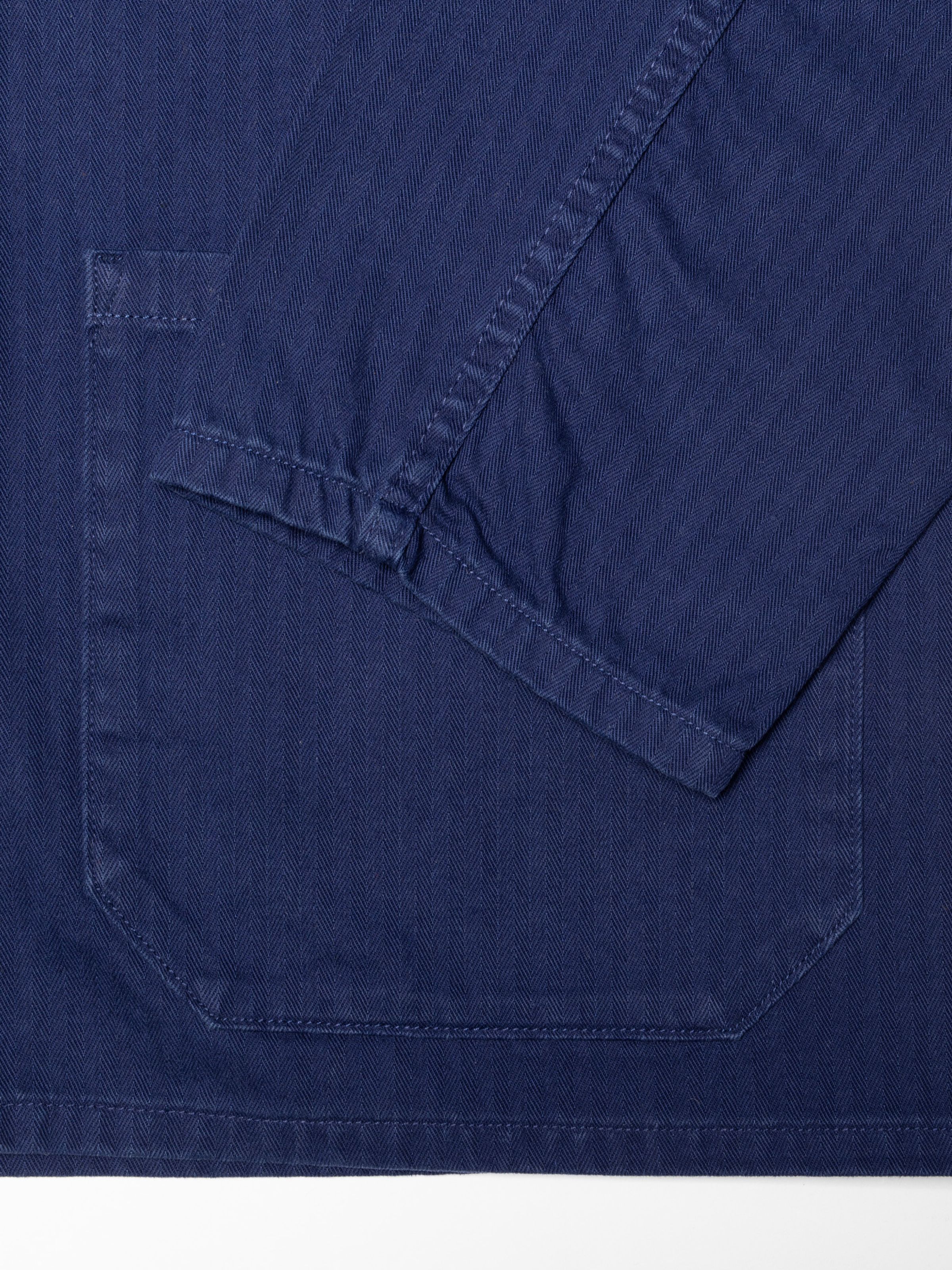 Nudie Jeans Buddy Chore Jacket Herringbone in Deep Blue, close-up of the sleeve, front pocket, and herringbone fabric.