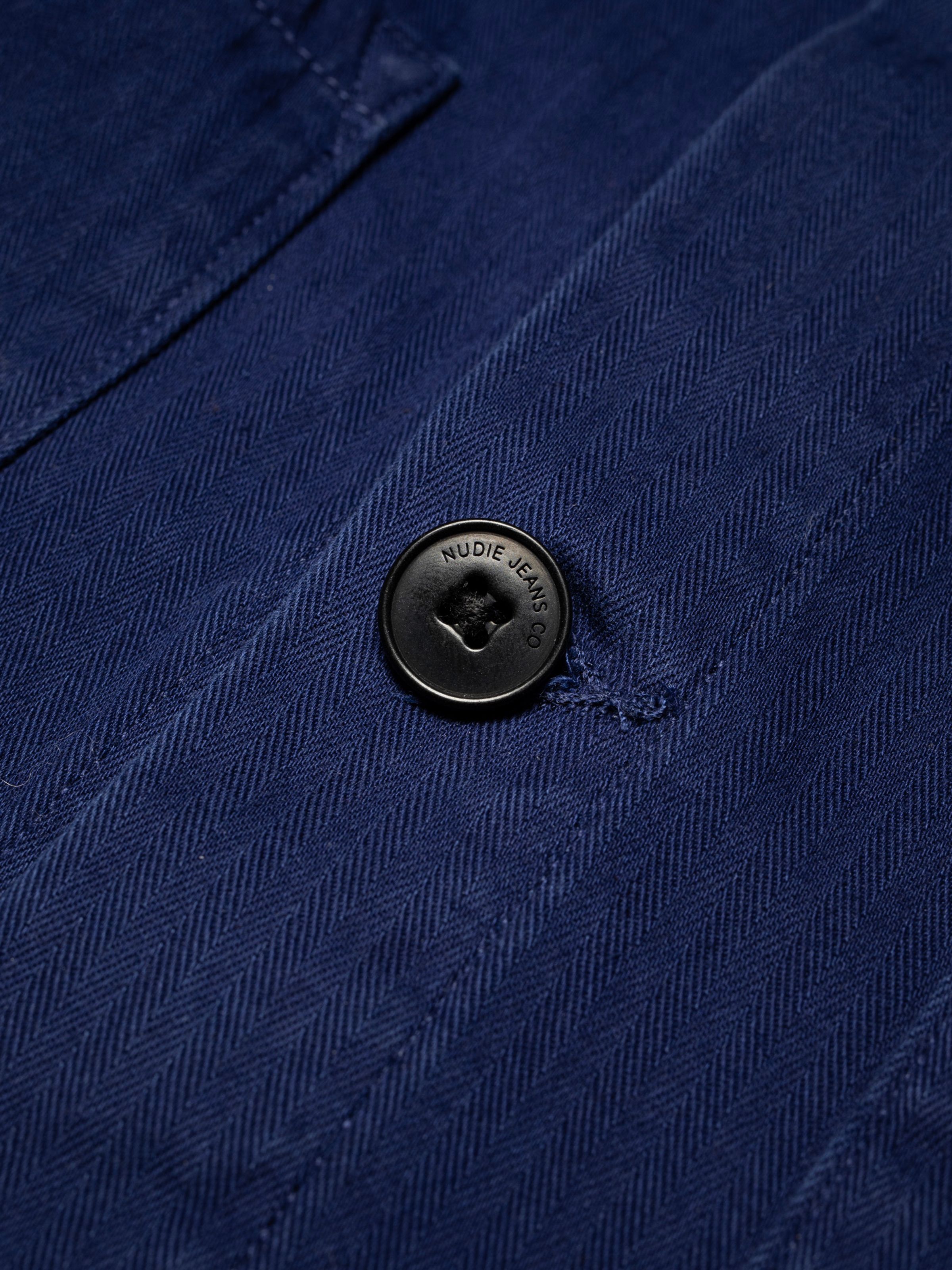 Nudie Jeans Buddy Chore Jacket Herringbone in Deep Blue, a men's jacket shown in a close-up of the fabric and corozo button.