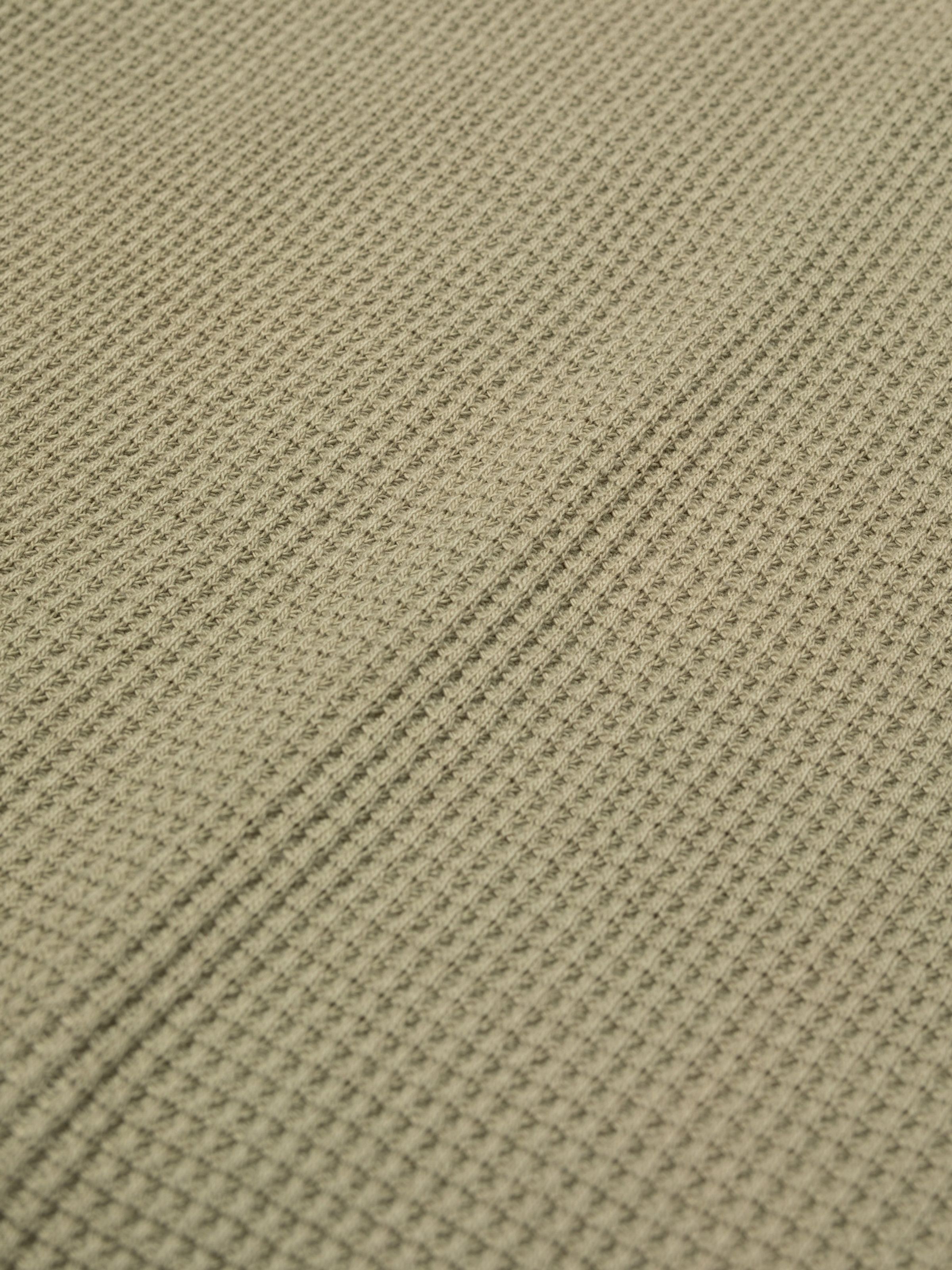Nudie Jeans LS Henley Waffle T-Shirt in Desert, a detailed close-up of the organic cotton waffle knit fabric.