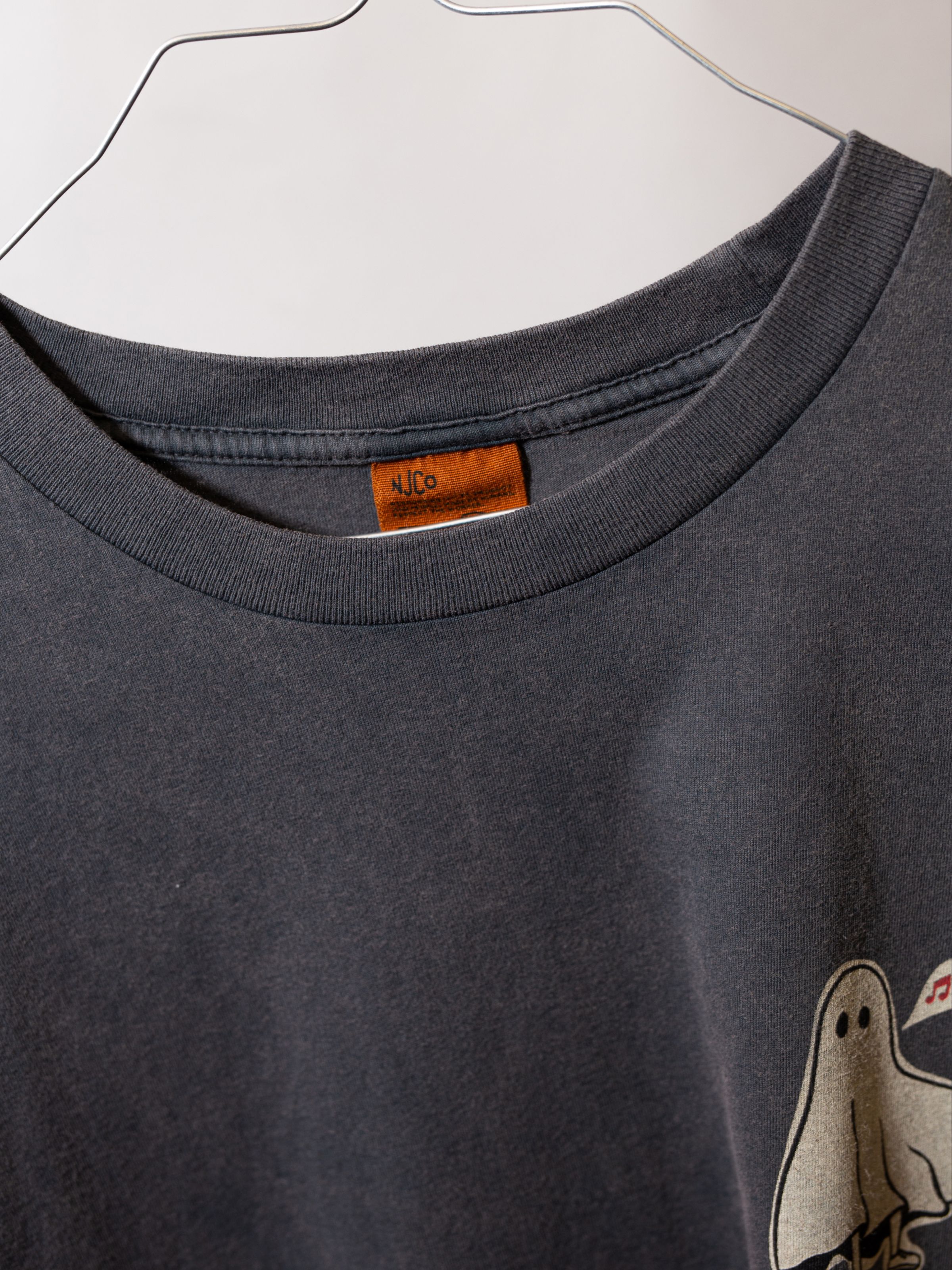 Nudie Jeans Roy Pale Tracks T-Shirt Antracite, a men's regular fit t-shirt, shown in a close-up of the collar and brand tag.