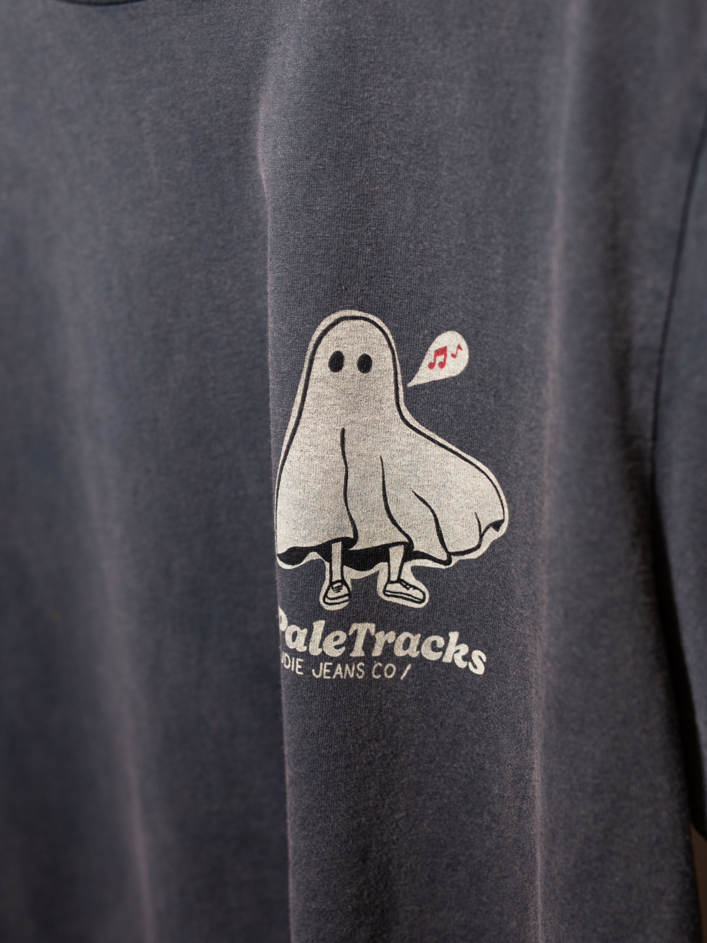 Nudie Jeans Roy Pale Tracks T-Shirt in Antracite, showing a close-up of the ghost and Pale Tracks logo printed on the chest.