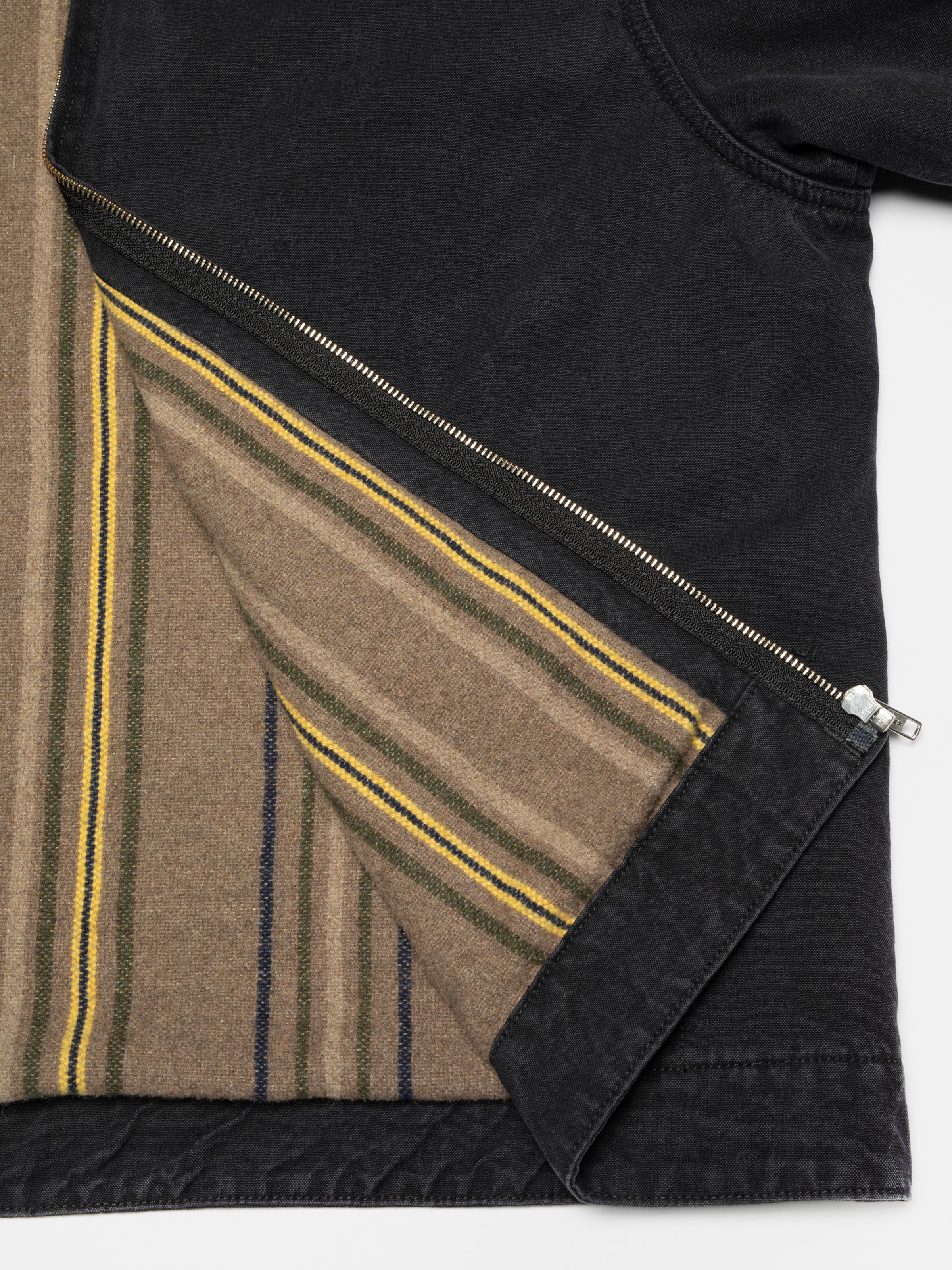 Nudie Jeans Blake Zip Jacket Duck Canvas in black, a detail shot showing the striped blanket lining and zipper.