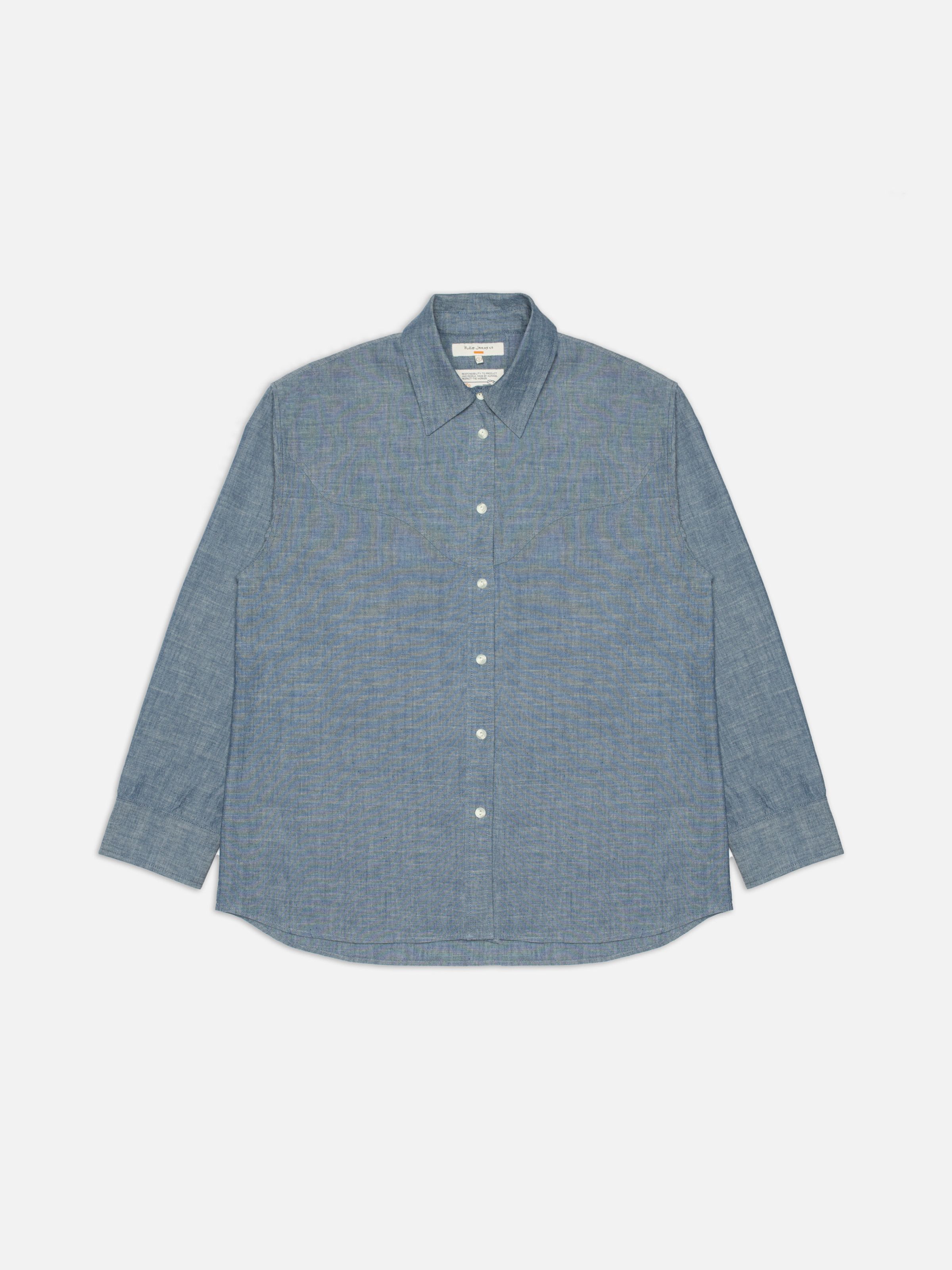 Nudie Jeans Daisy Chambray Western Shirt, a women's relaxed fit shirt in blue chambray, shown laid flat.
