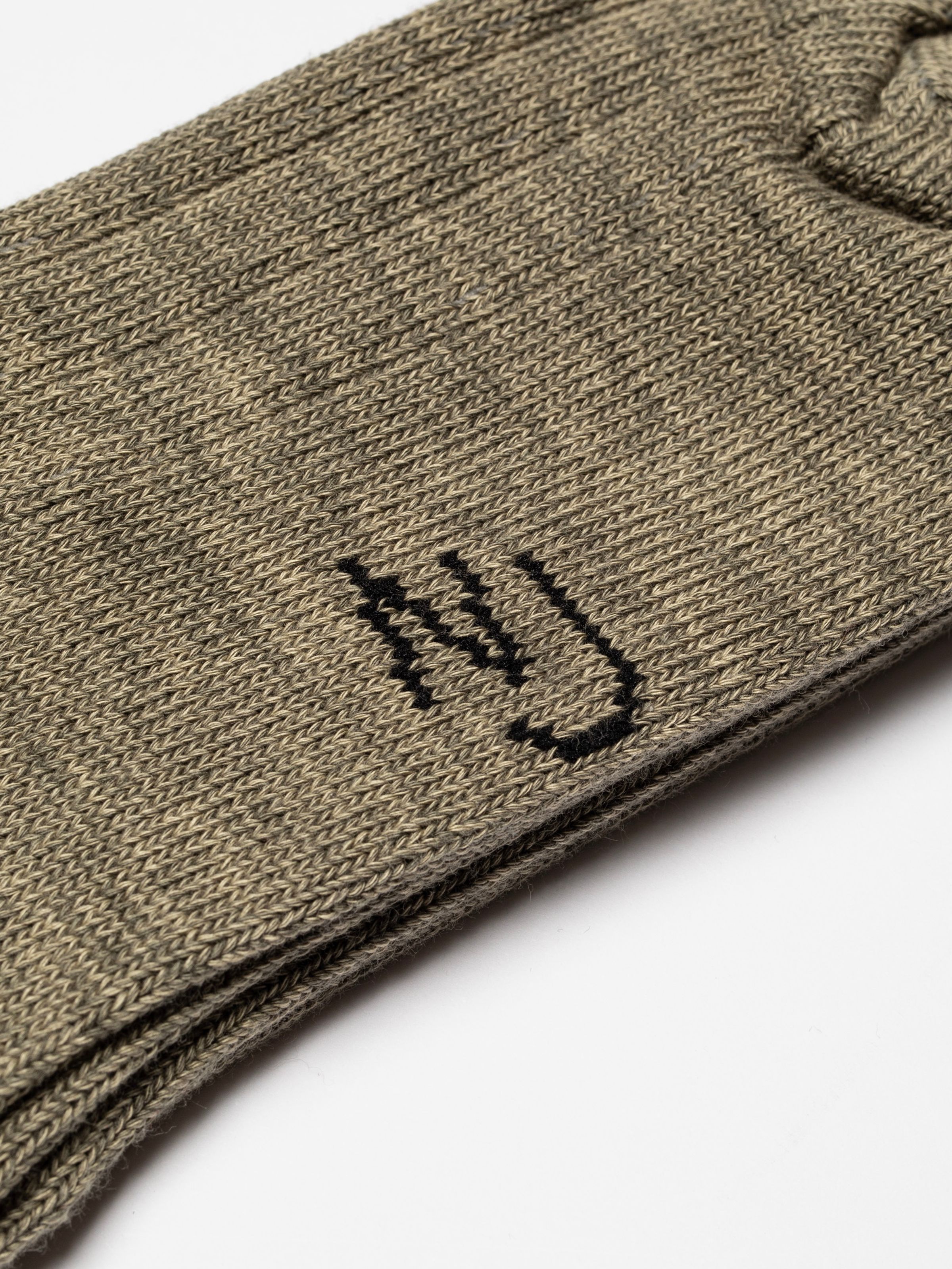 Nudie Jeans Broad Ribbed Socks in Desert, a close-up showing the ribbed texture and embroidered NJ logo.