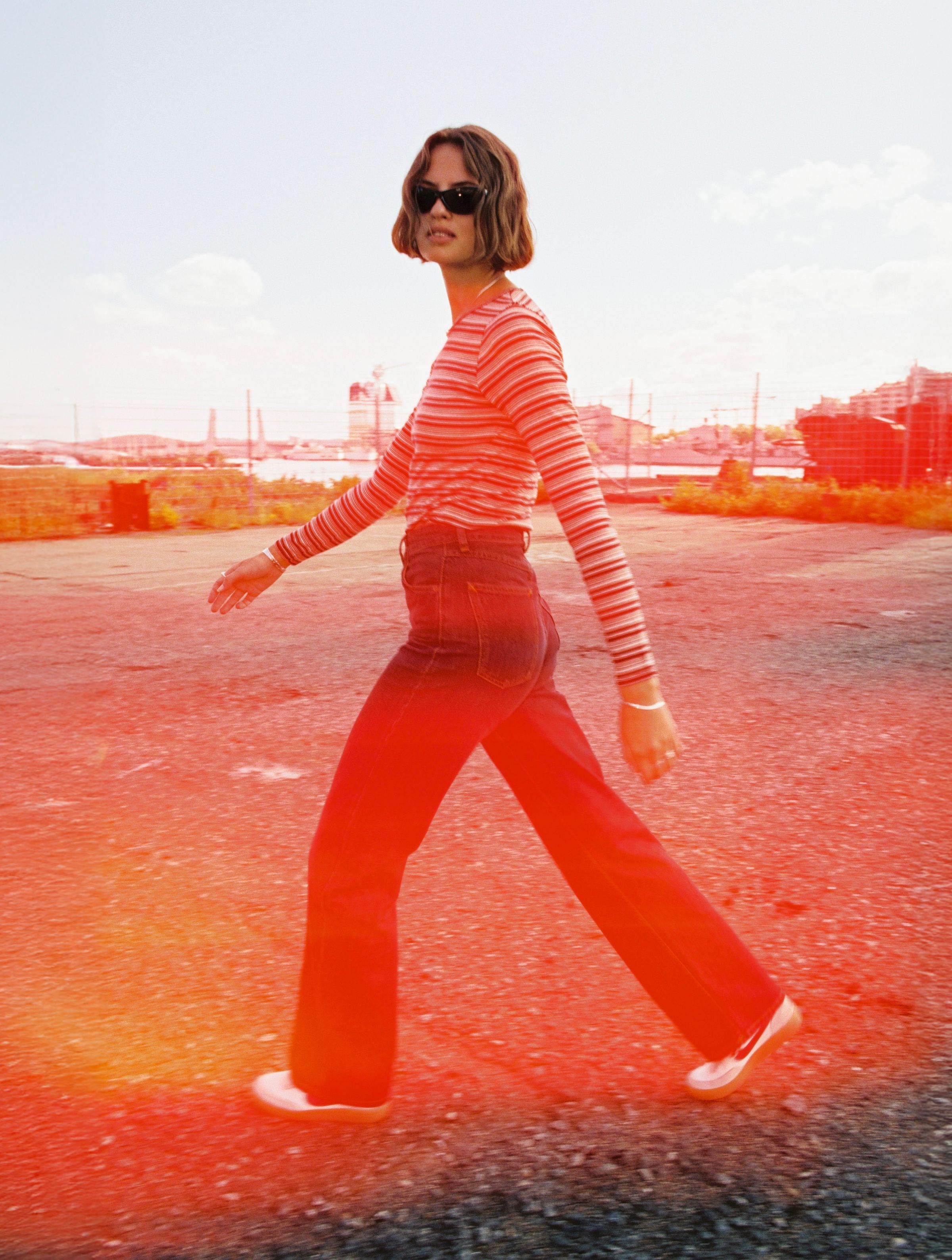Nudie Jeans Jessy LS T-Shirt Striped Rib in Wine, a women's long-sleeve top worn by a model walking outdoors.