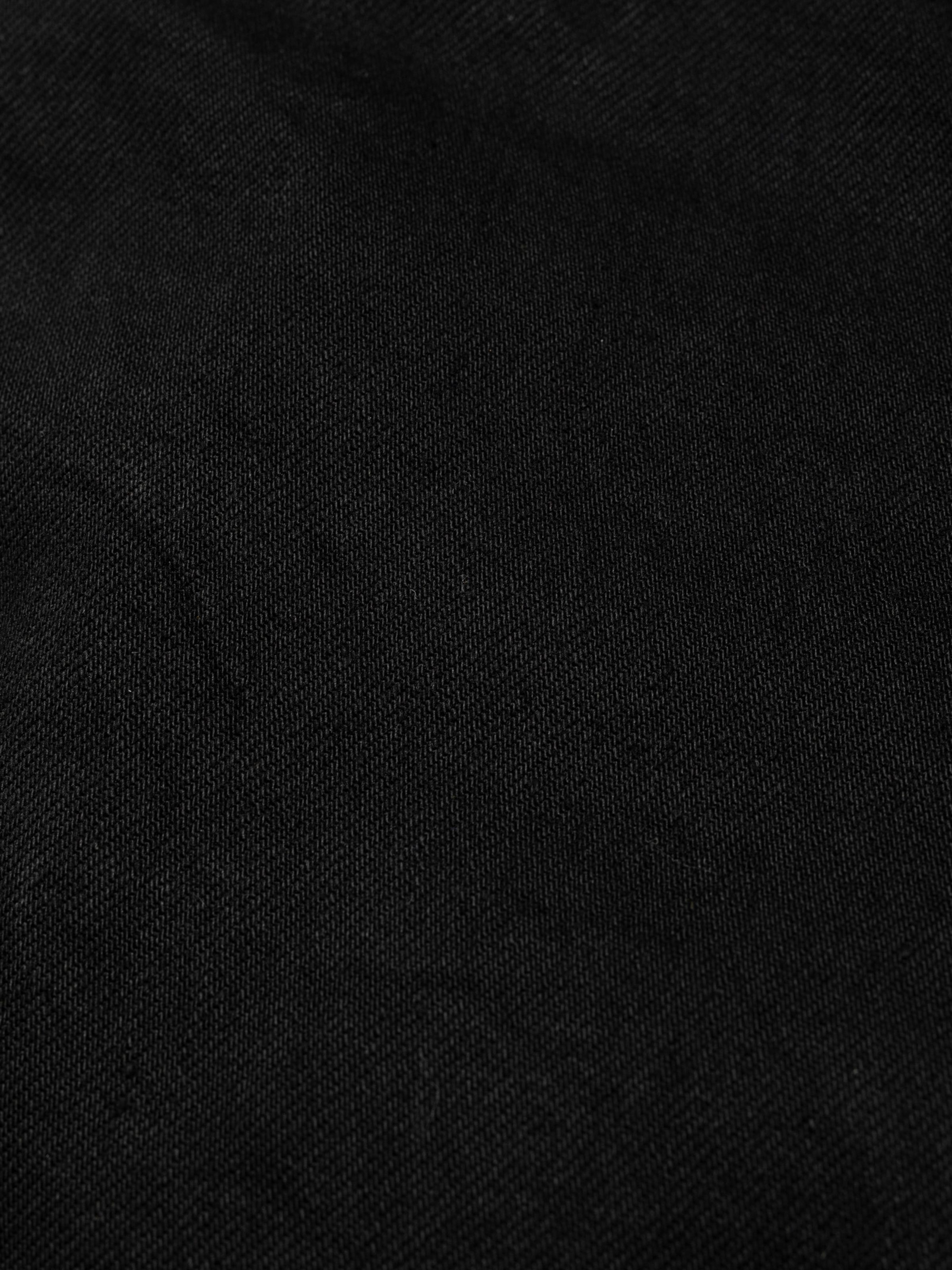Nudie Jeans Tuff Tony Black Water, a pair of men's loose fit jeans in black denim, shown in a close-up fabric detail.