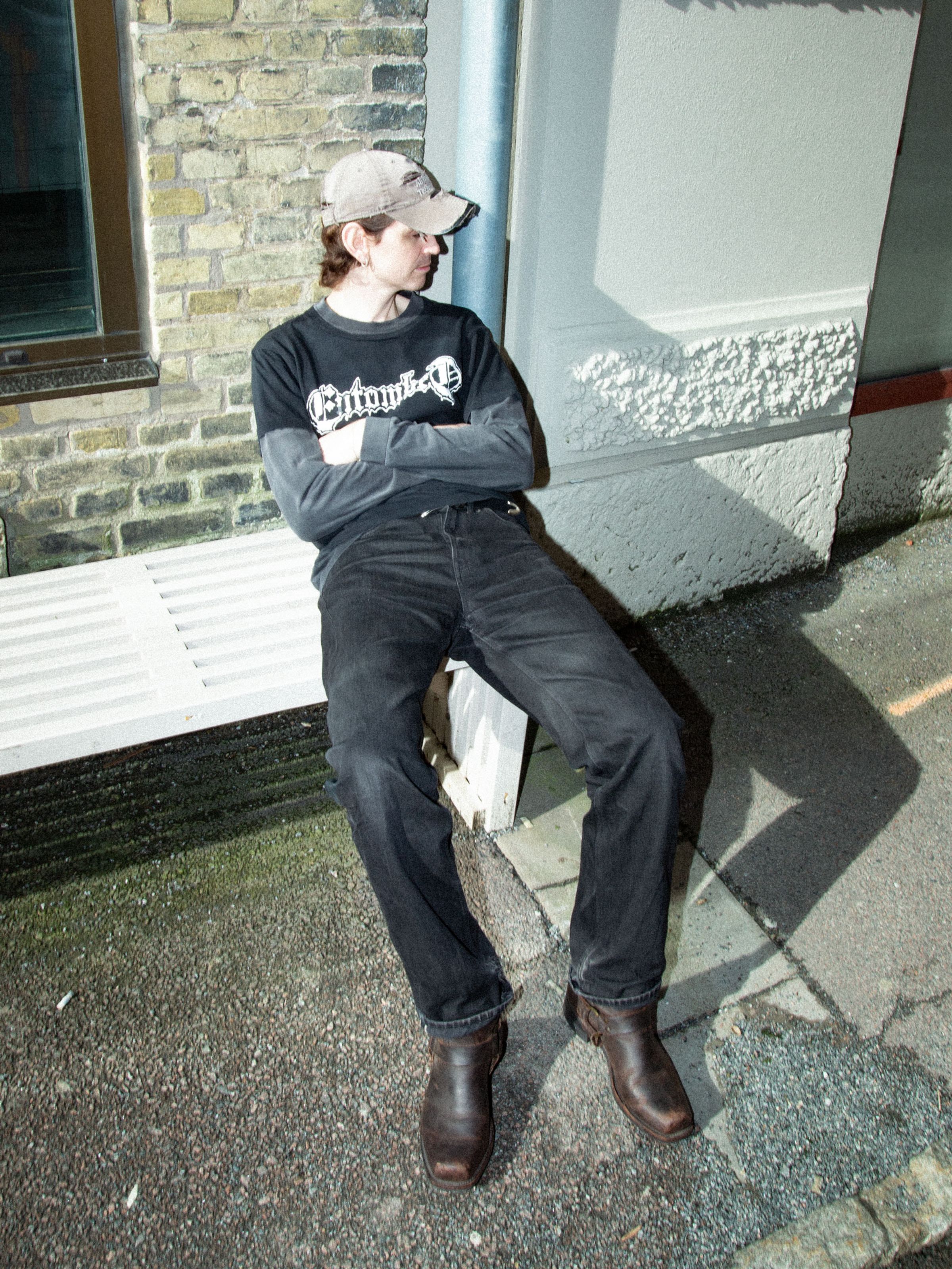 Nudie Jeans Tuff Tony Dry Black Selvage, men's loose-fit selvedge jeans shown on a model seated on a white bench.