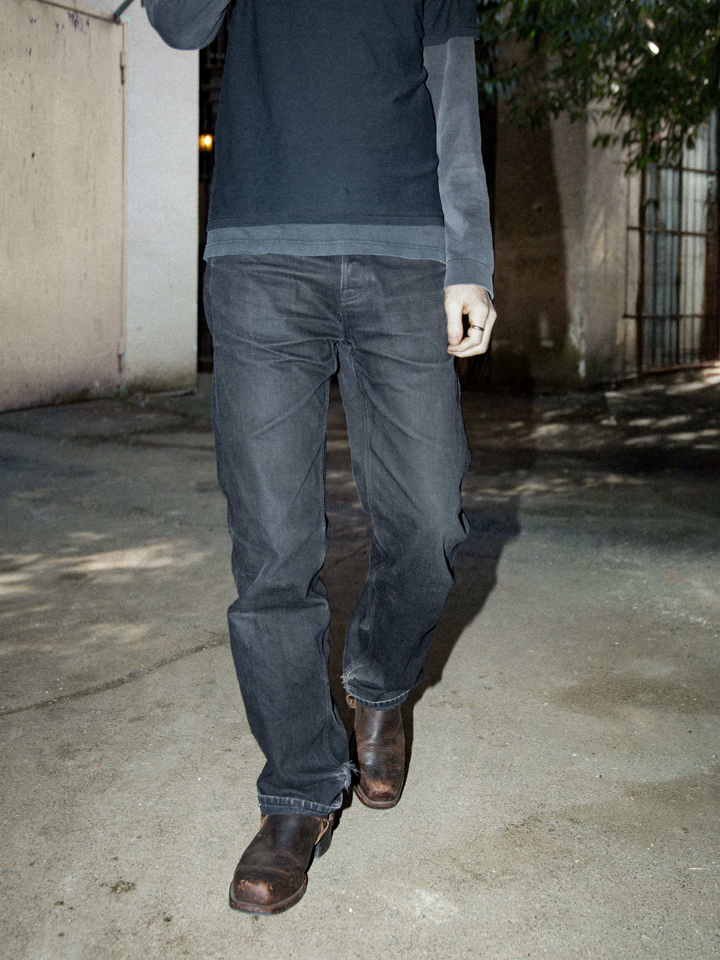 Nudie Jeans Tuff Tony Dry Black Selvage, men's loose-fit wide-leg jeans in black rigid selvedge denim walking outdoors.