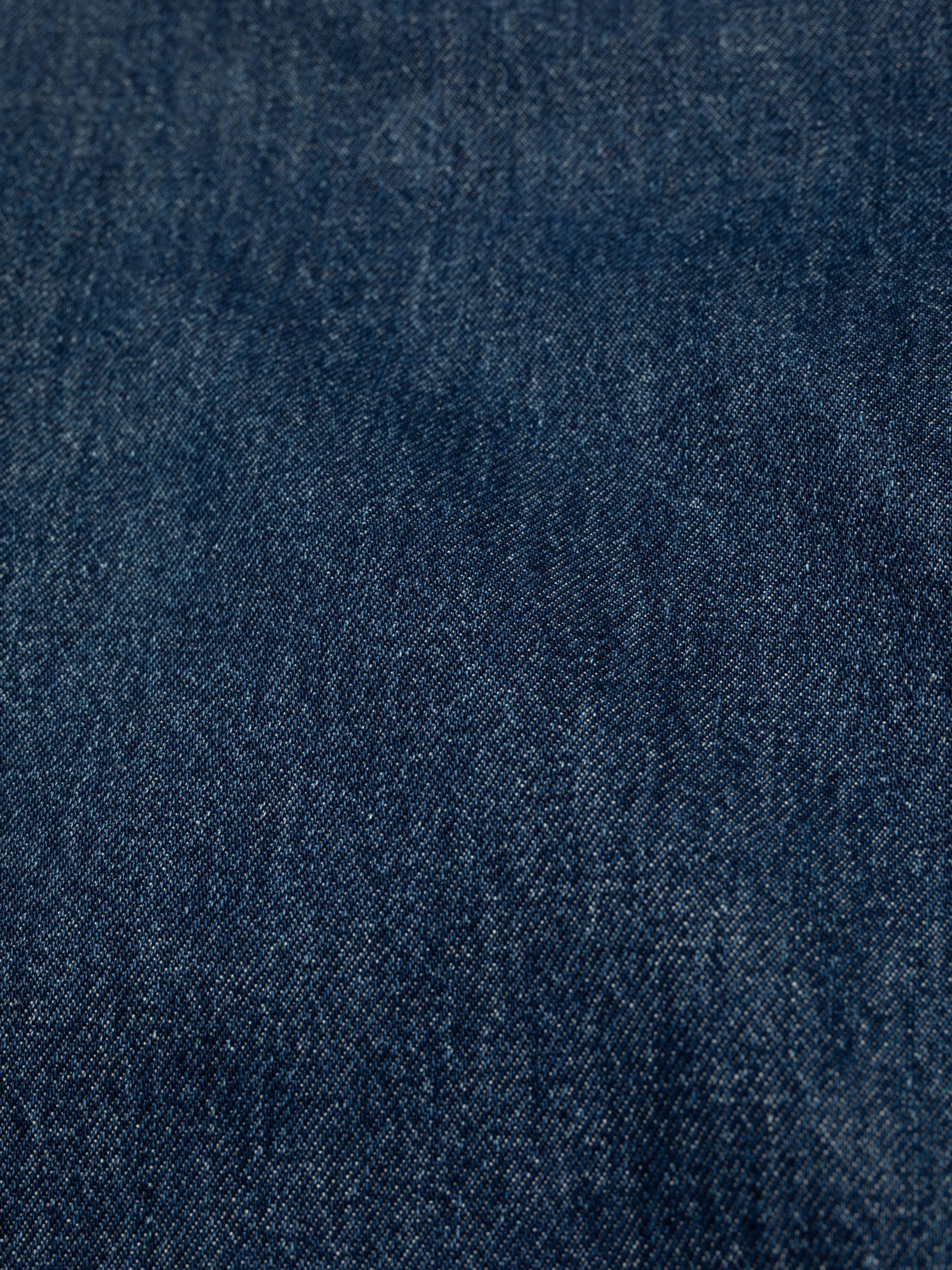 Nudie Jeans Breezy Britt in Evening Jazz, a close-up detail shot of the dark blue stonewashed denim fabric.
