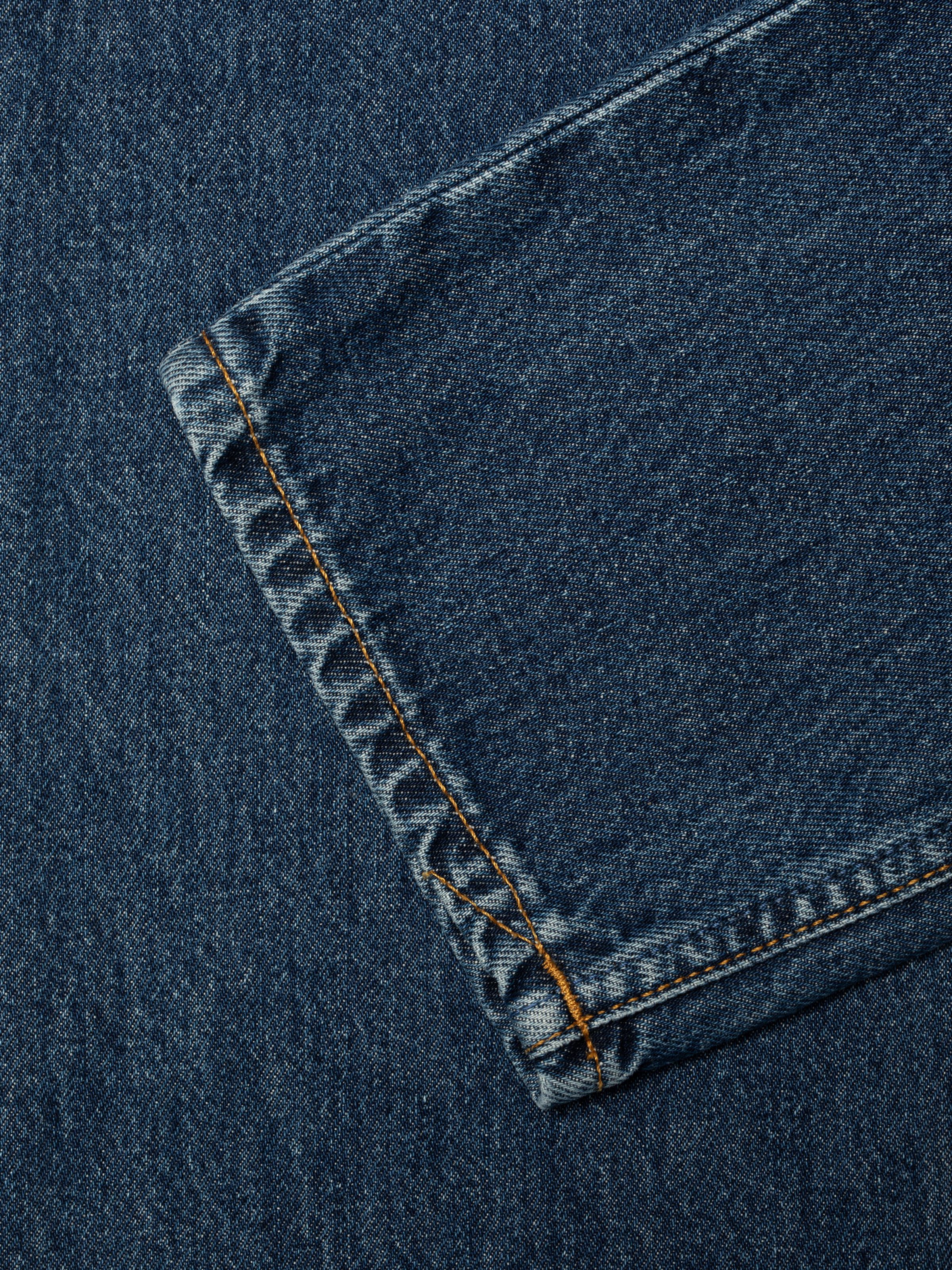 Nudie Jeans Breezy Britt Evening Jazz, a women's regular fit tapered jean, shown in a close-up of the back pocket detail.