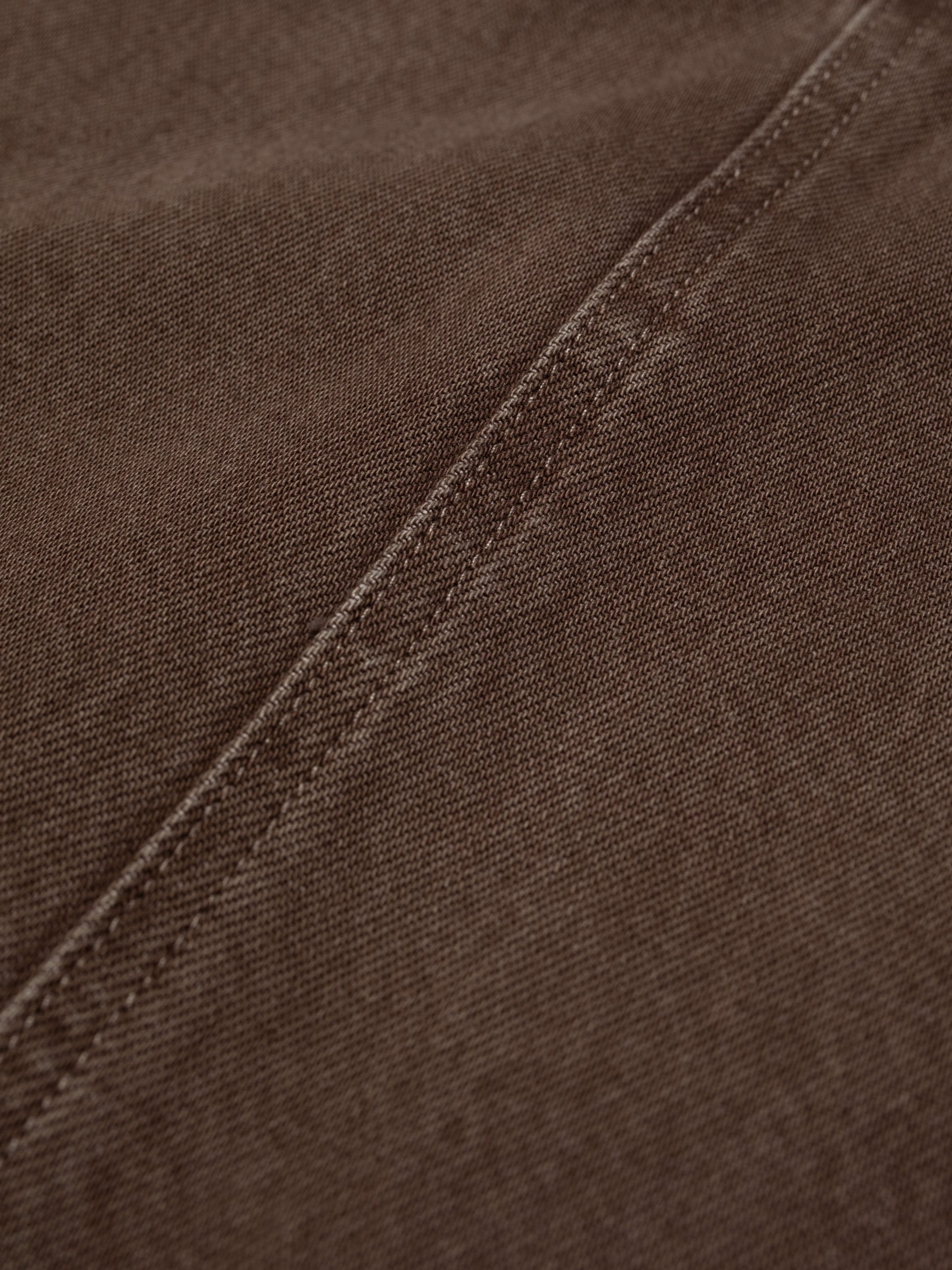 Nudie Jeans Inger Dungarees Dress Espresso, a close-up detail shot of the brown denim fabric and seam stitching.