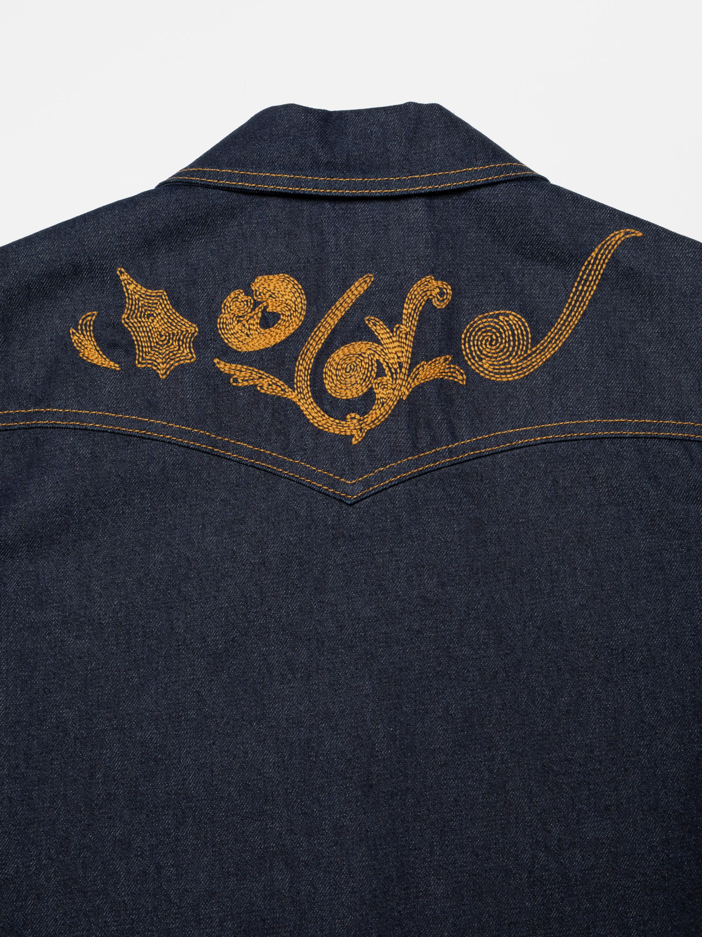 Nudie Jeans Kelly Western Jacket Embroidery Blue, a women's denim jacket, shown in a close-up of the back yoke embroidery.