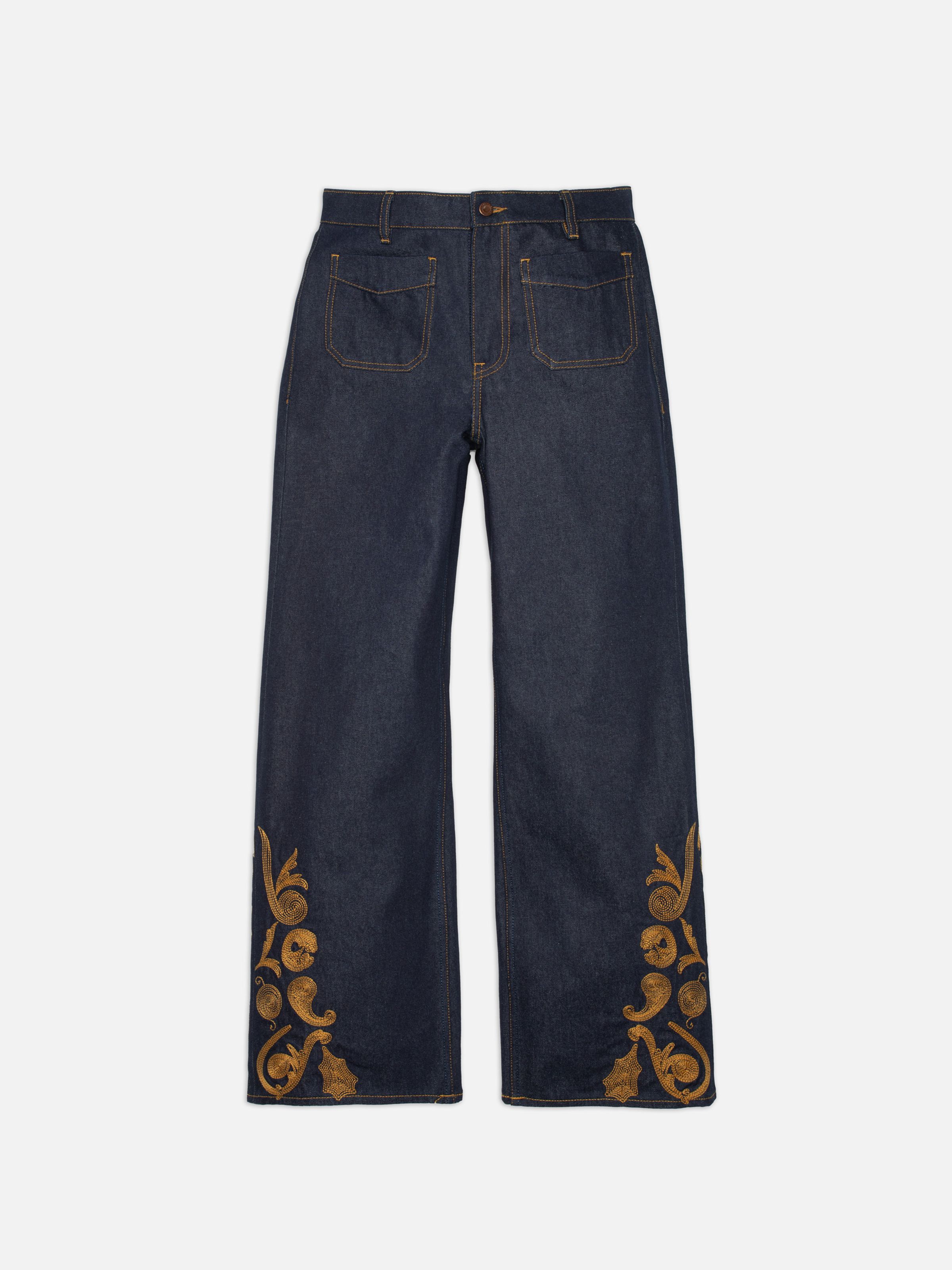 Nudie Jeans Holly Western Pants, a pair of women's flared leg pants in dry blue denim with embroidery, shown laid flat.