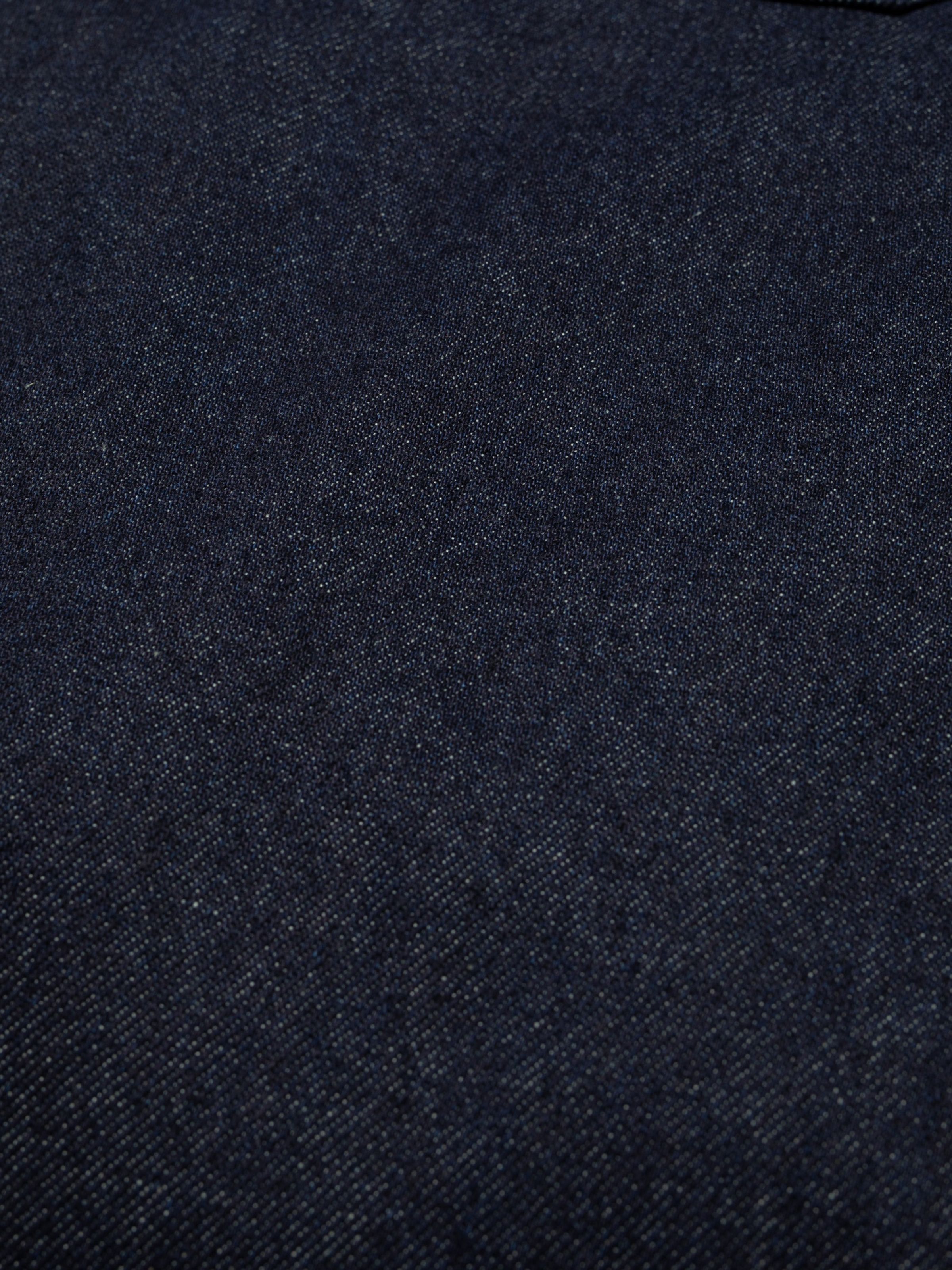 Nudie Jeans Holly Western Pants, a pair of women's flared leg pants in dry mid-blue denim, showing a close-up of the fabric.