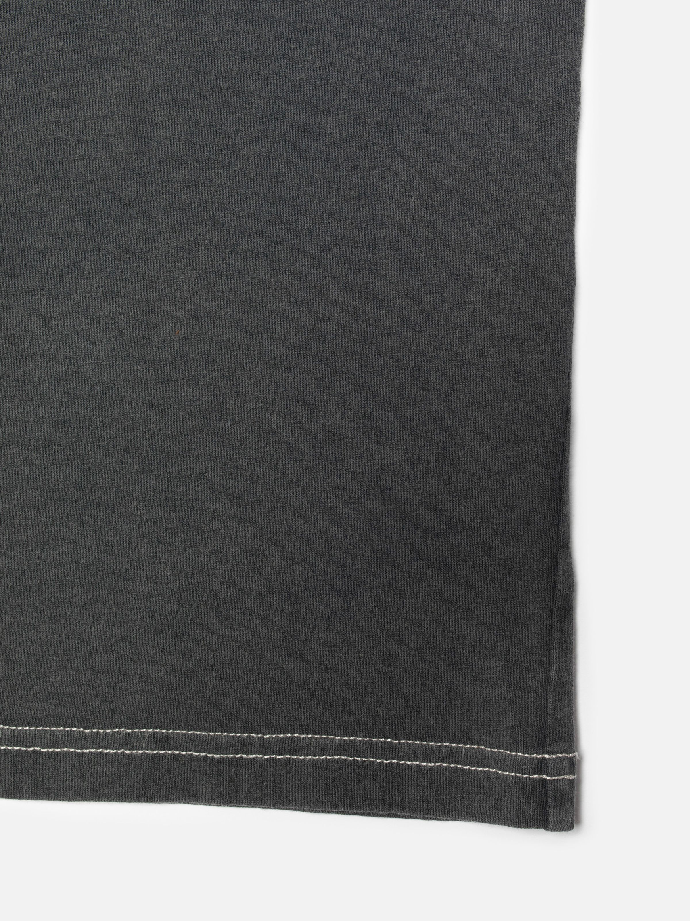 Nudie Jeans Koffe Knock-Topus T-Shirt in Antracite, a close-up of the hem showing the contrasting off-white stitching.