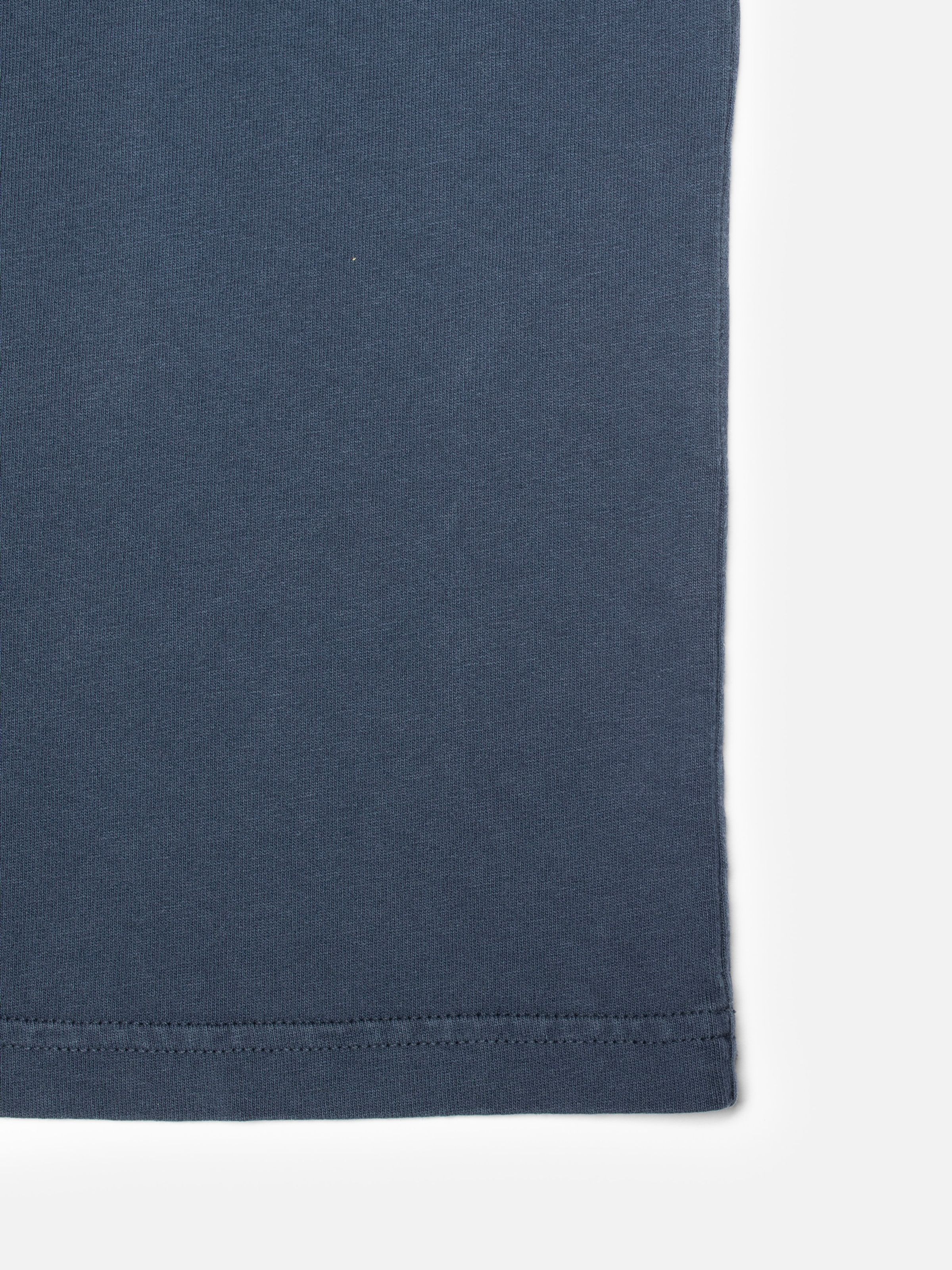 Nudie Jeans Roy Icy Tracks T-Shirt in dark blue, showing a close-up of the fabric texture and hem stitching.