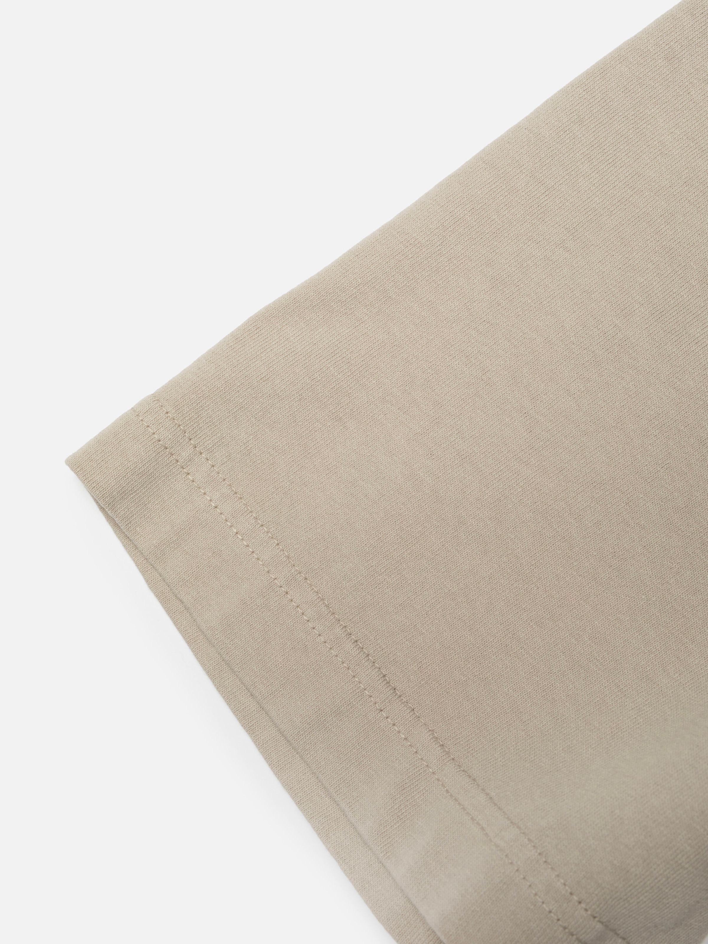 Nudie Jeans Uno Everyday T-Shirt in Sand, close-up of the hem and organic cotton jersey fabric.