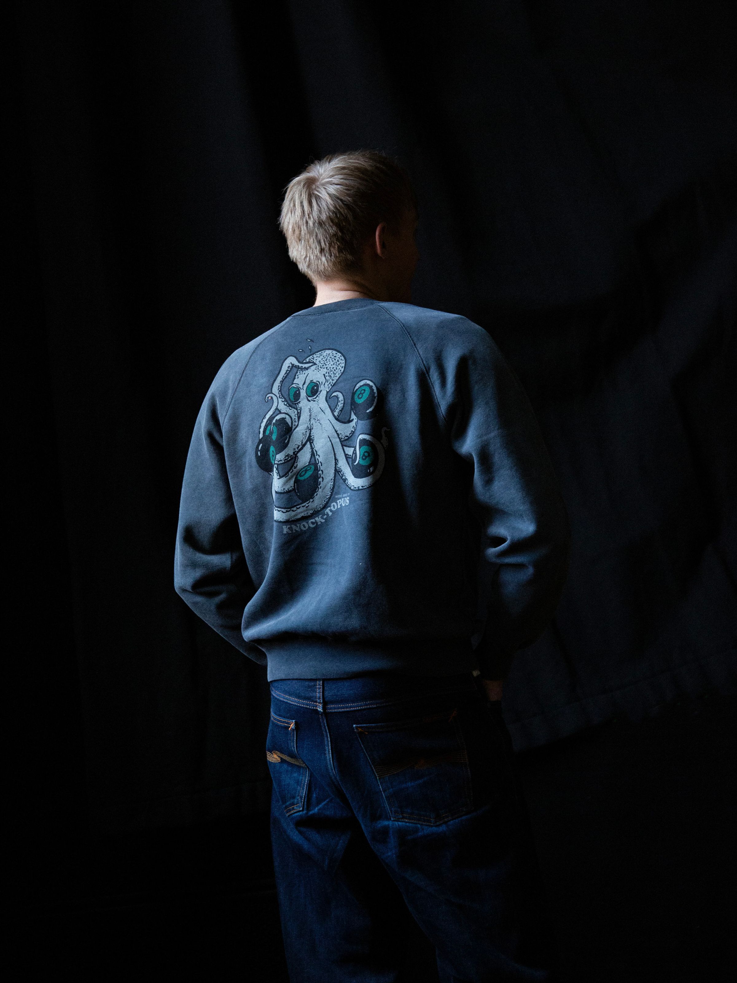 Nudie Jeans Palle Sweatshirt Knock-Topus, a men's sweatshirt in a faded black shown from the back on a model.