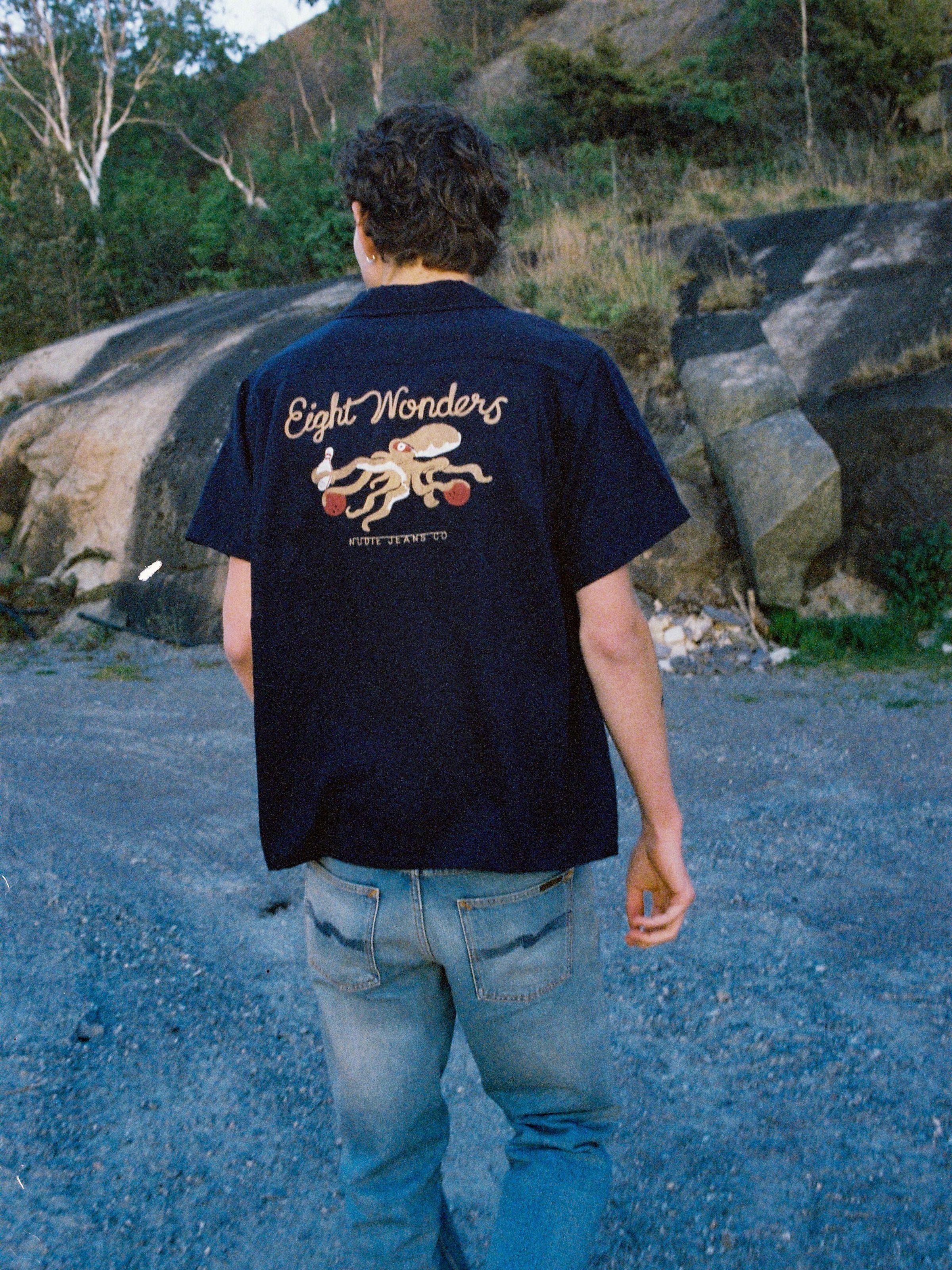 Nudie Jeans Arthur Bowling Shirt 8 Wonders in Navy, Herren-Bowlinghemd, von hinten an einem Model im Freien gezeigt.