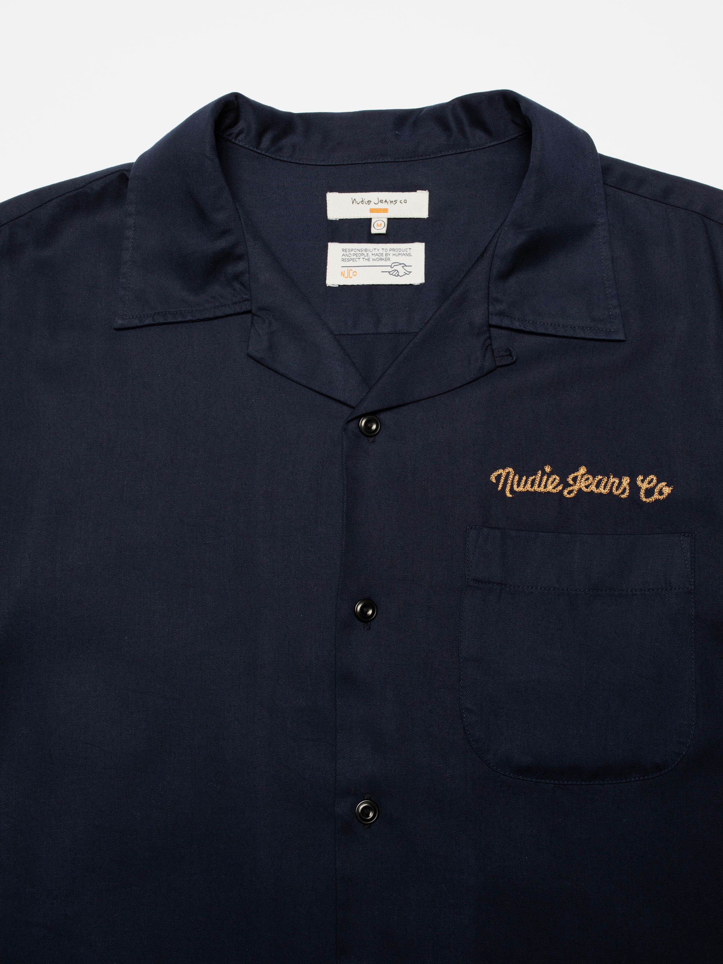 Nudie Jeans Arthur Bowling Shirt 8 Wonders in navy, showing a close-up of the camp collar and chain stitch chest embroidery.