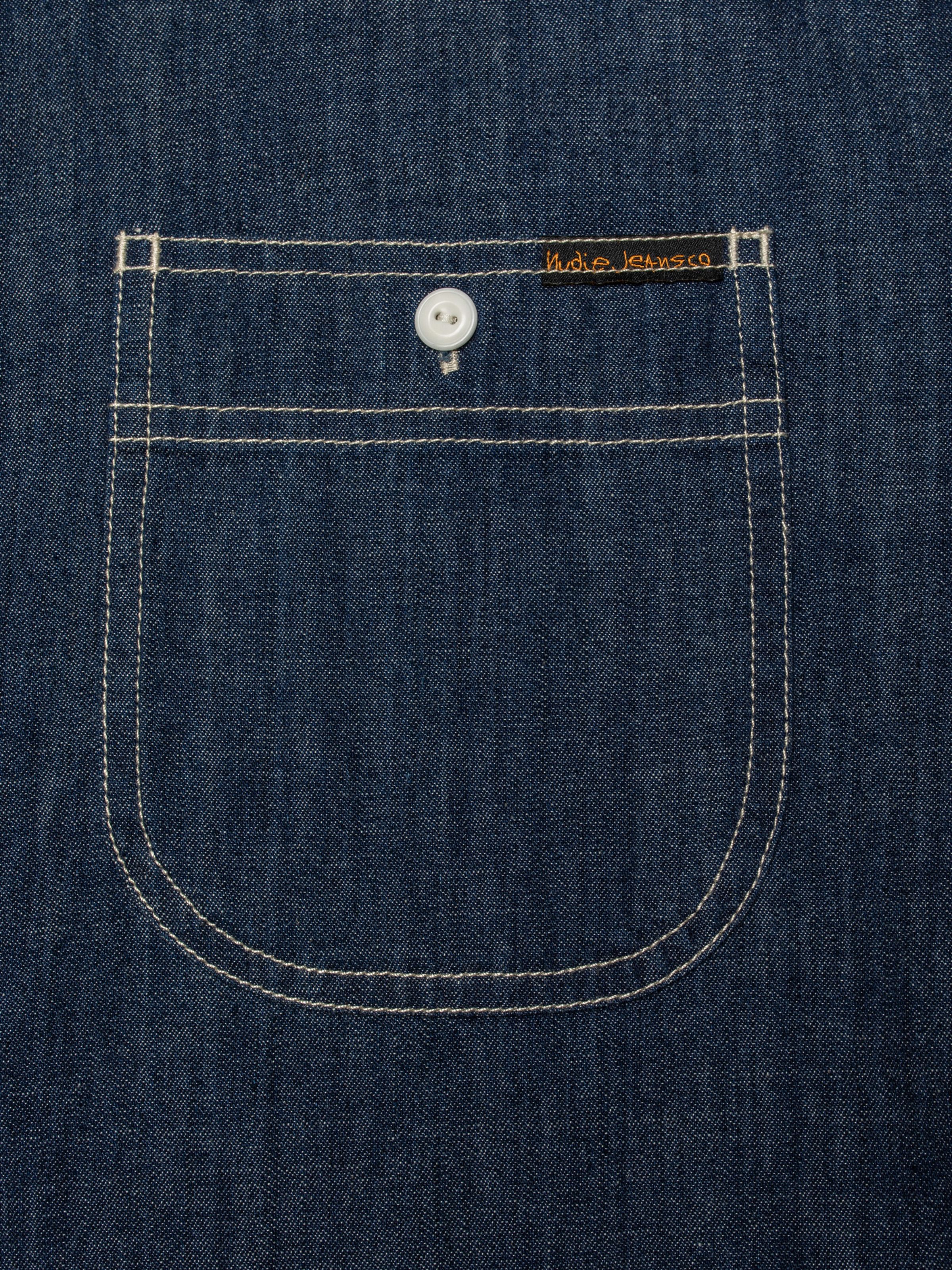 Nudie Jeans Julian Denim Shirt Rinsed, close-up of the chest pocket showing the Nudie Jeans logo tab.