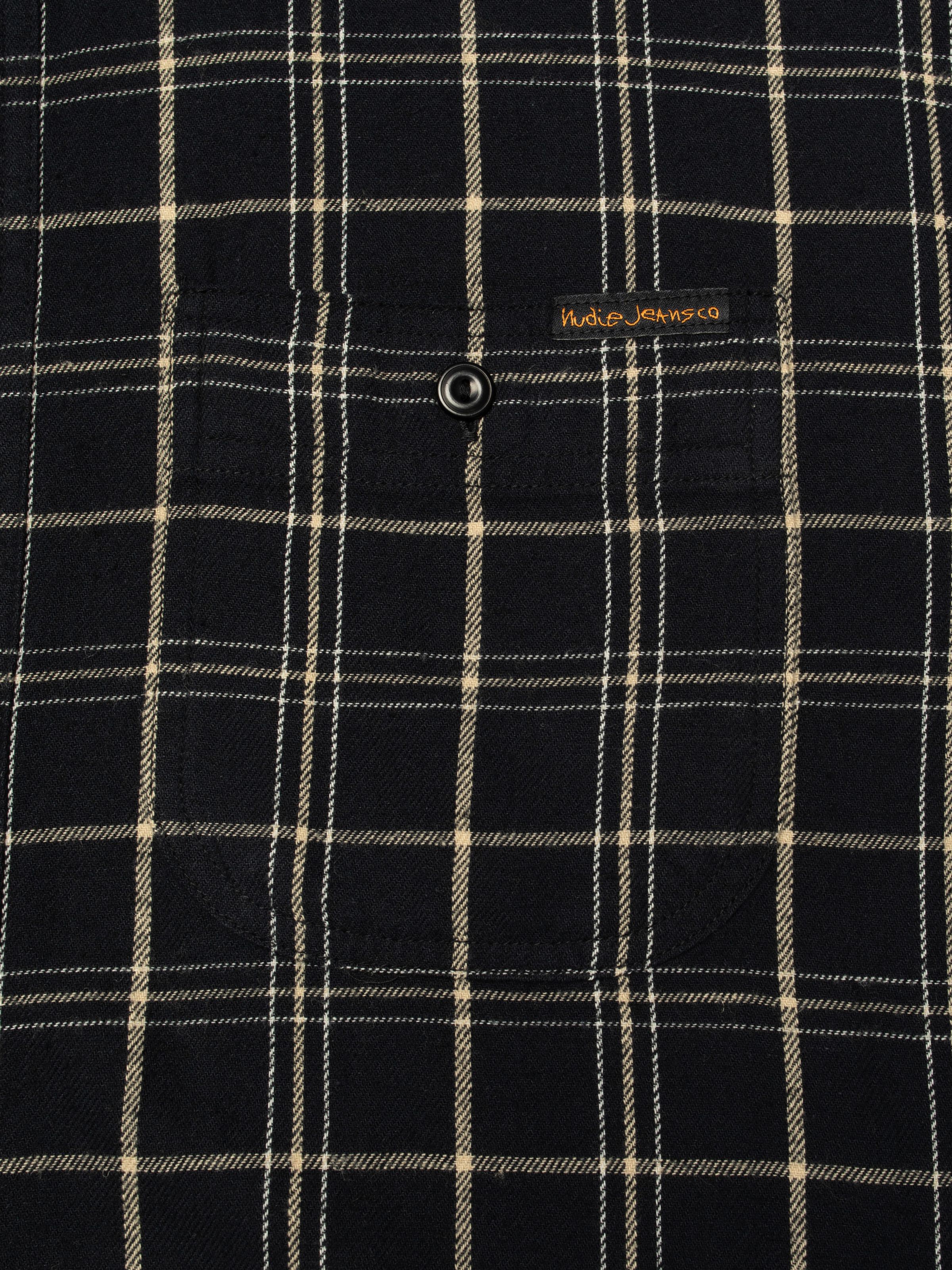 Nudie Jeans Julian Worker Shirt Checked, close-up of the checked fabric and chest pocket with logo tab.