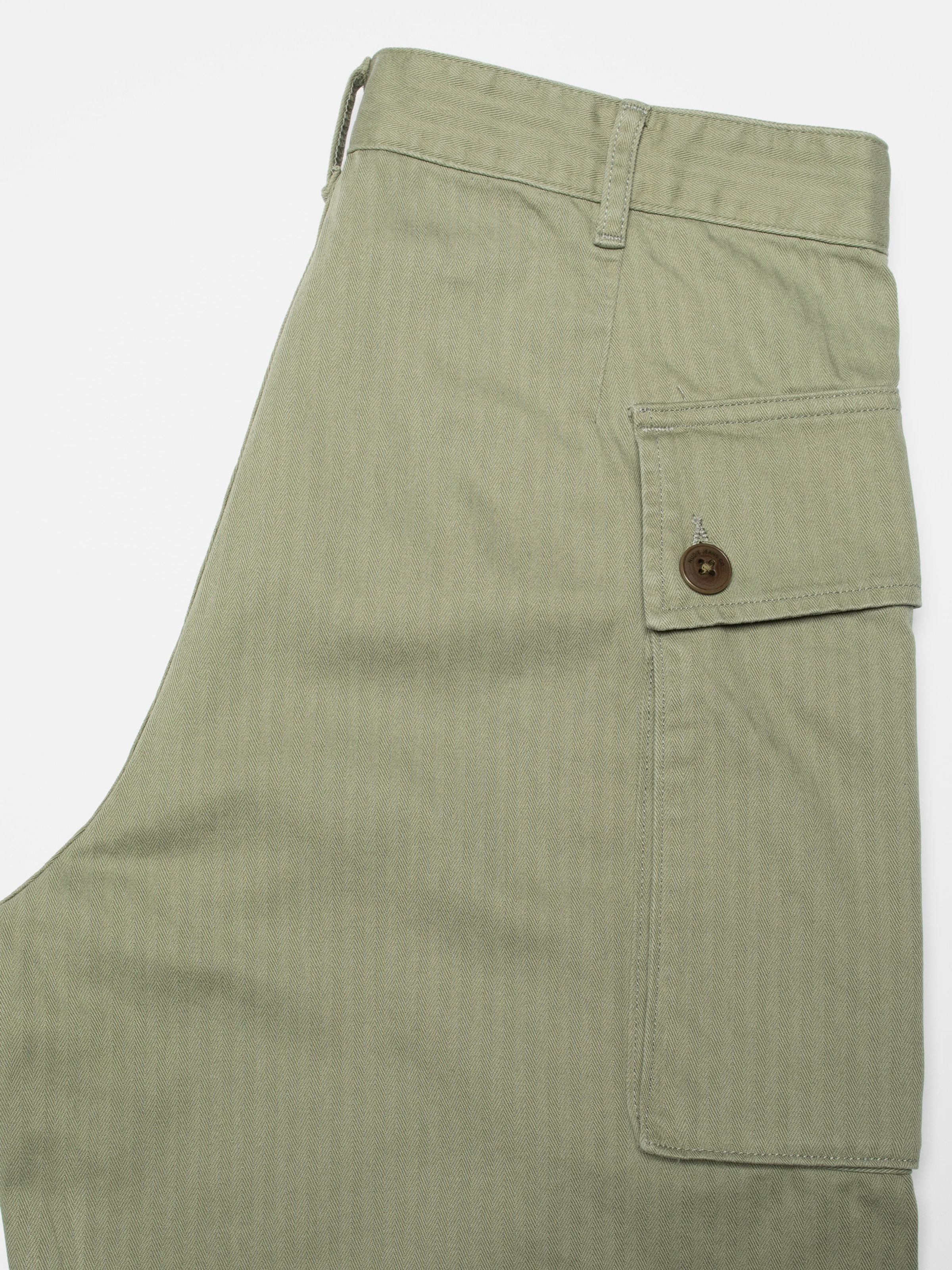 Nudie Jeans Loud Larry Pants in Pale Green, close-up showing the side cargo pocket and the herringbone twill fabric.