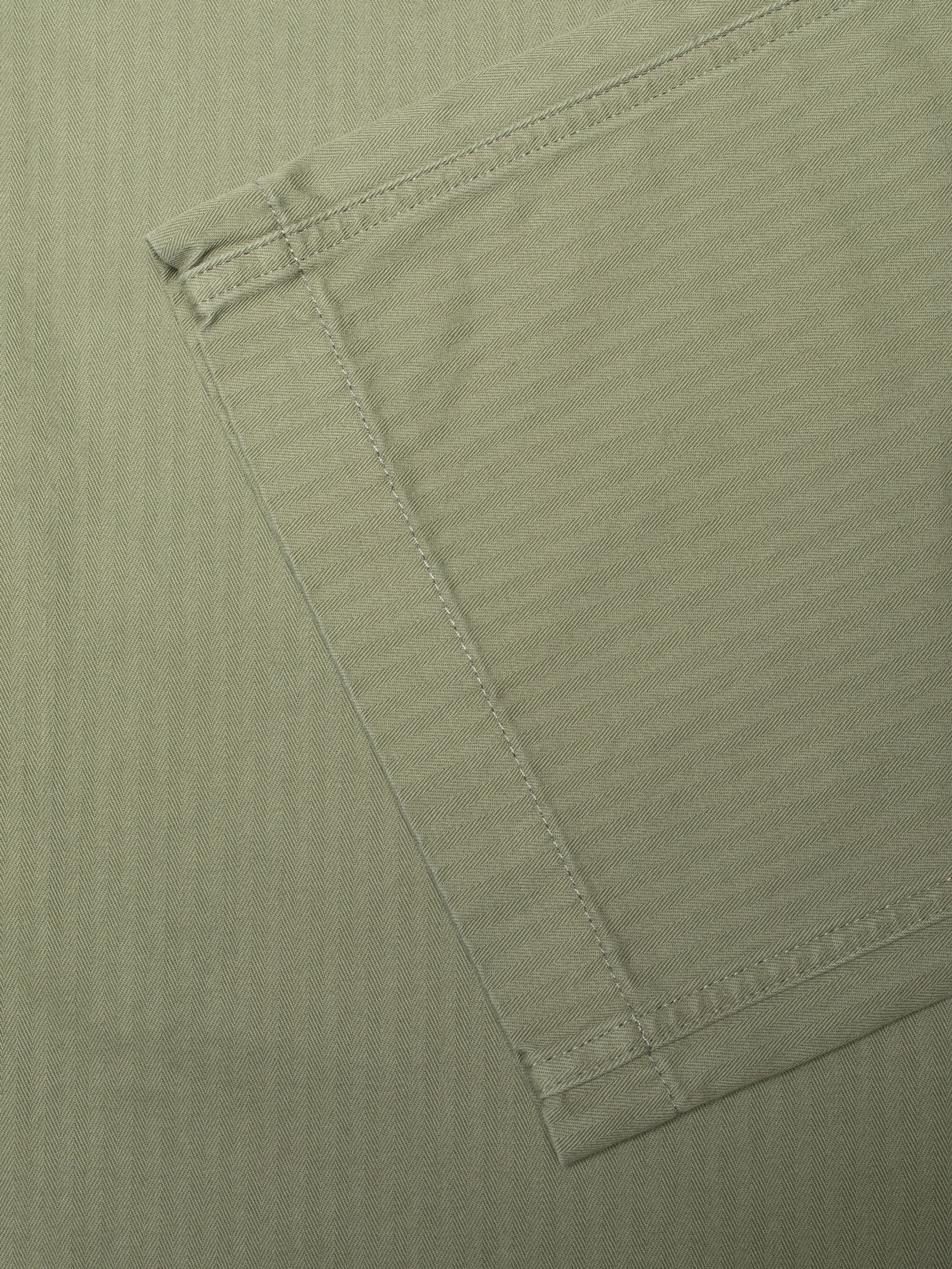 Nudie Jeans Loud Larry Pants Pale Green, close-up of the herringbone twill fabric showing the pocket corner stitching.
