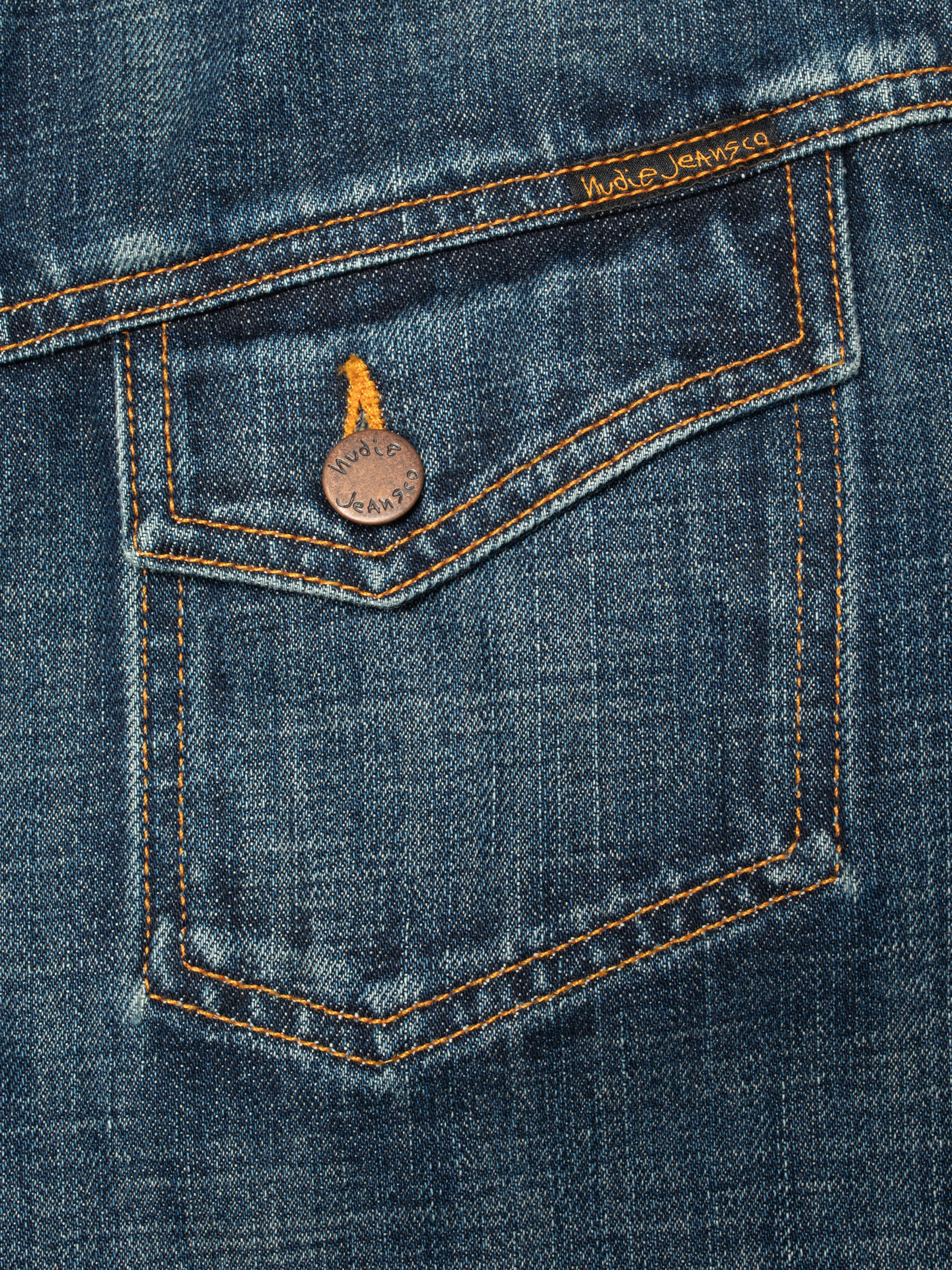 Nudie Jeans Conny Denim Jacket Heavy Used, close-up of the chest pocket with copper button and orange stitching.
