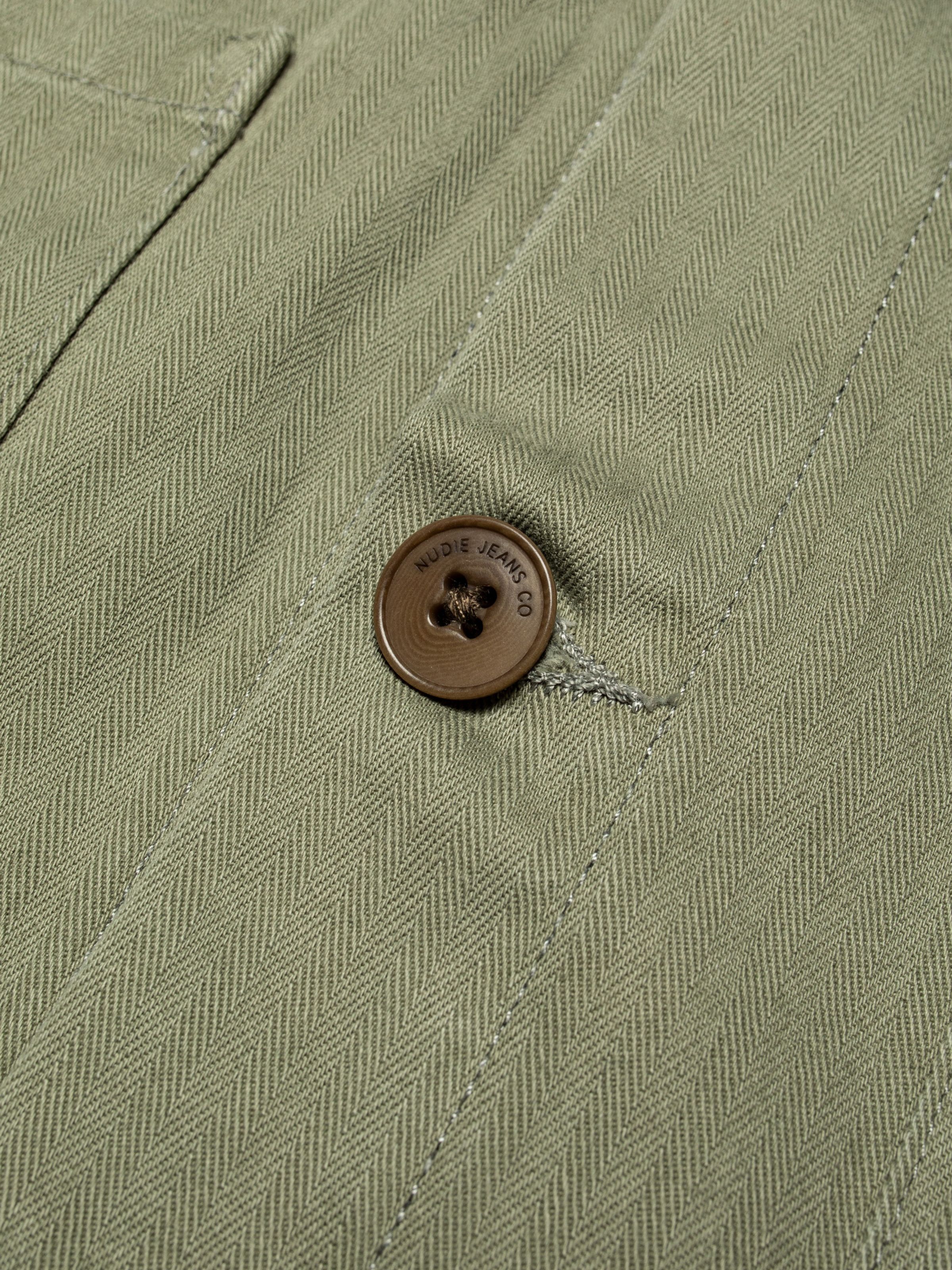 Nudie Jeans Buddy Chore Jacket Herringbone in Pale Green, close-up of the herringbone fabric and Corozo button detail.