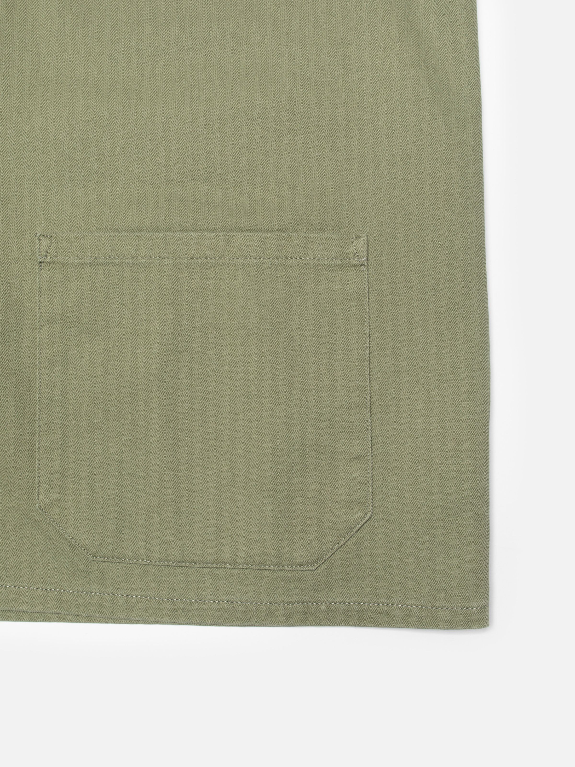 Nudie Jeans Buddy Chore Jacket Herringbone in Pale Green, close-up of the front pocket and herringbone fabric detail.
