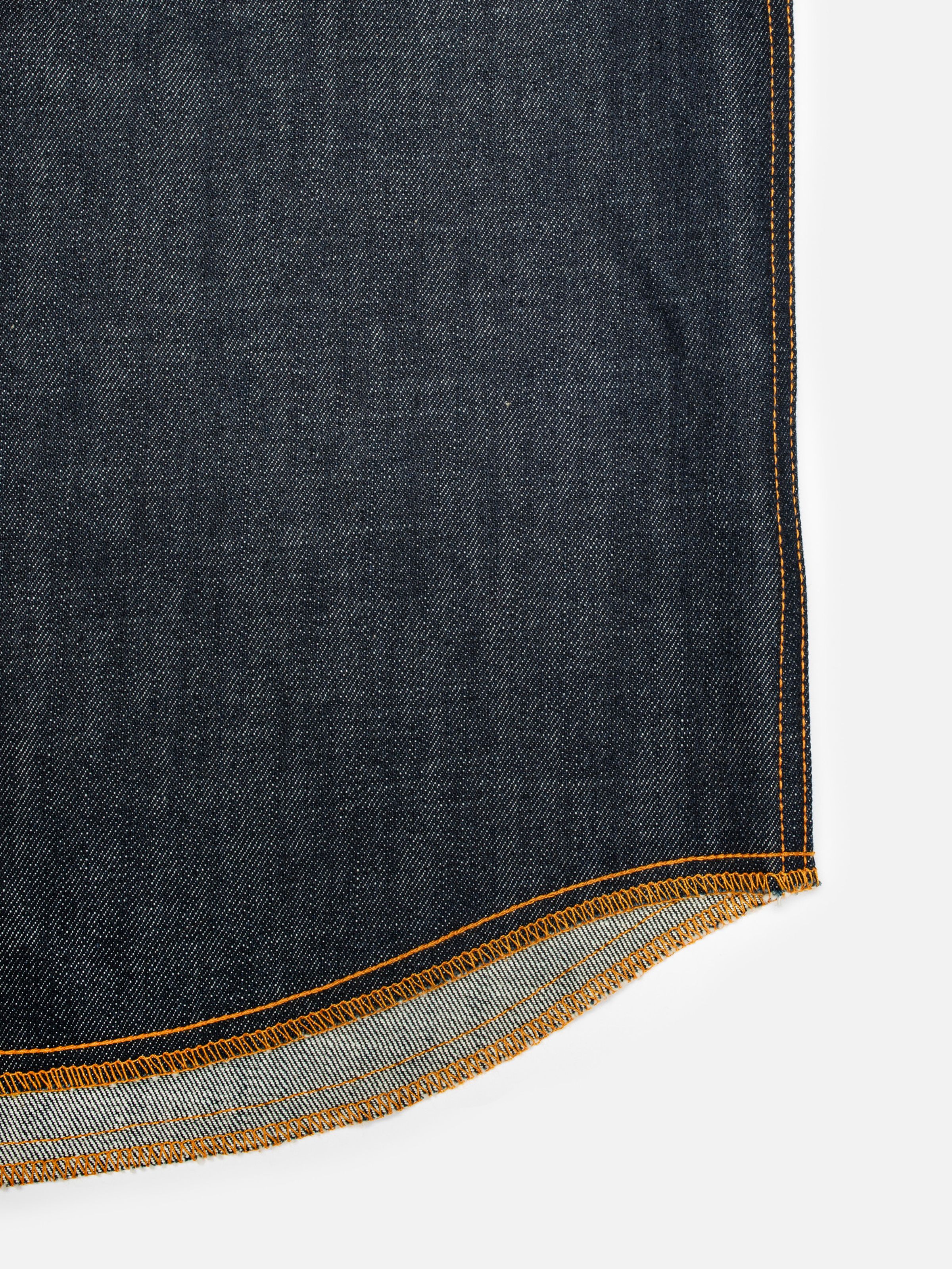 Nudie Jeans Gunnar Denim Shirt Dry Streaky, a close-up view of the curved hem and orange stitching detail.