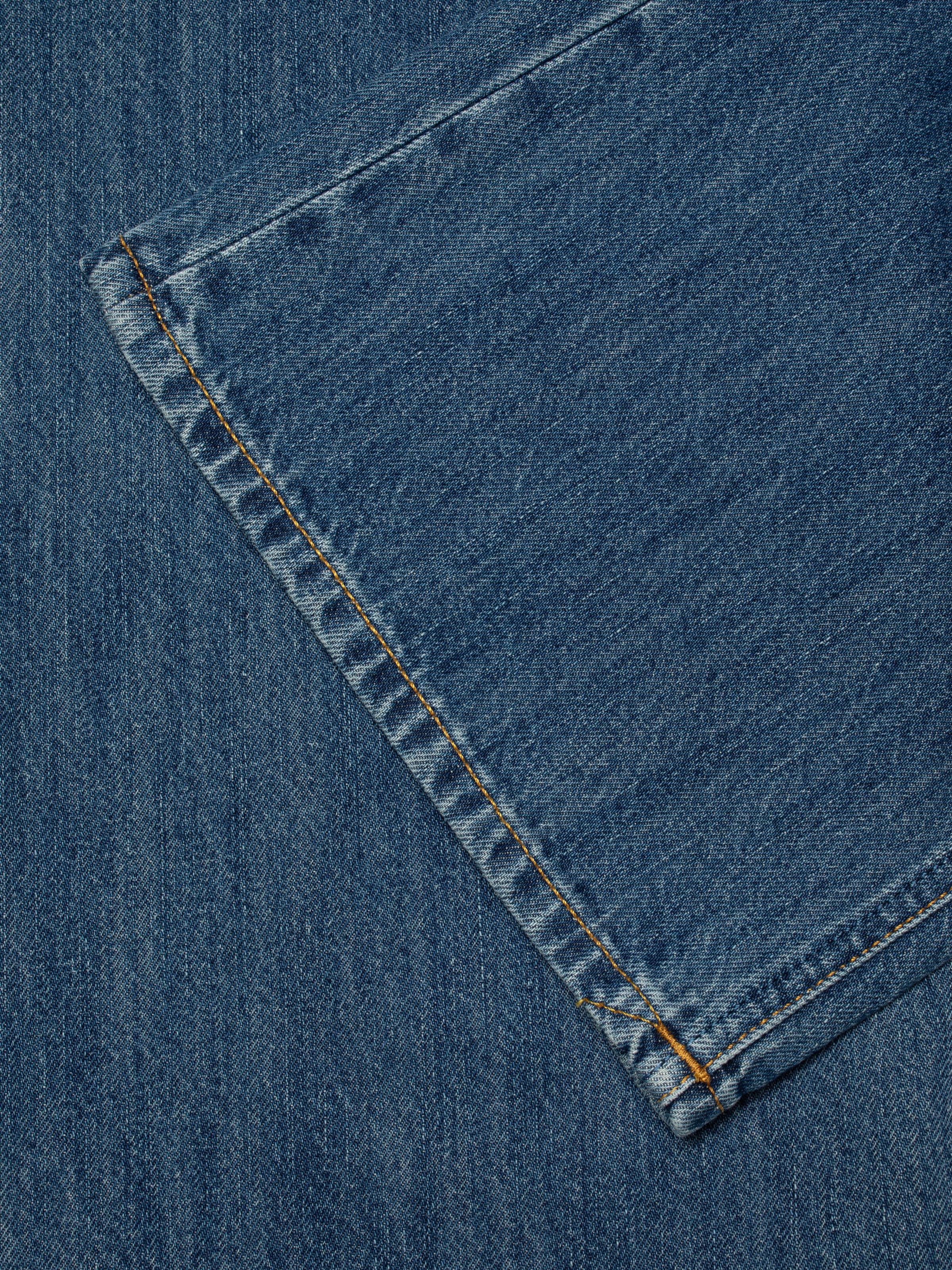 Nudie Jeans Wide Heidi Clear Skies, a close-up of the light blue wash denim and tobacco thread stitching.