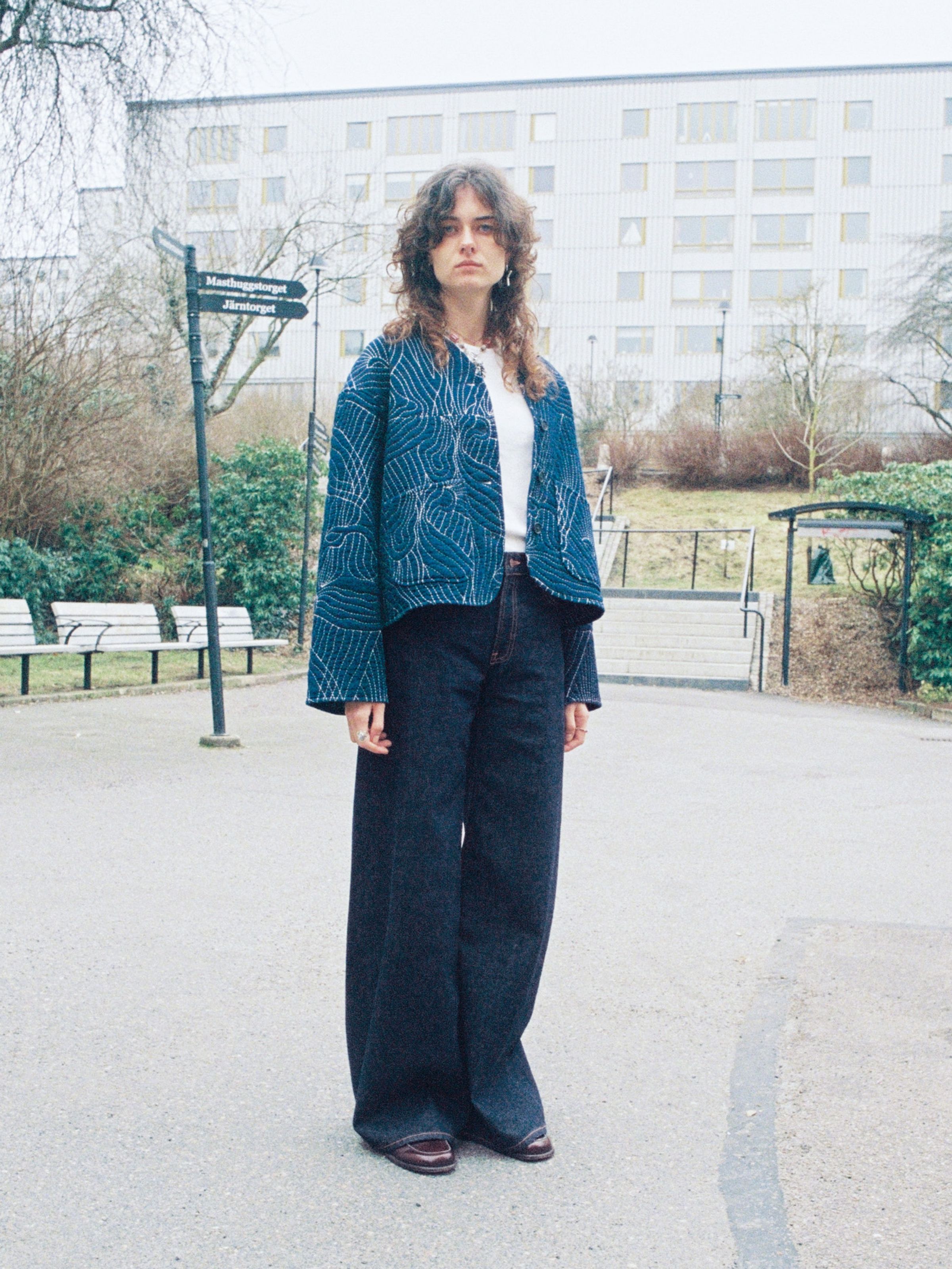 Nudie Jeans Sonic Sue One Wash, Damenjeans in dunklem Blau, draußen getragen mit einer gesteppten Jacke.