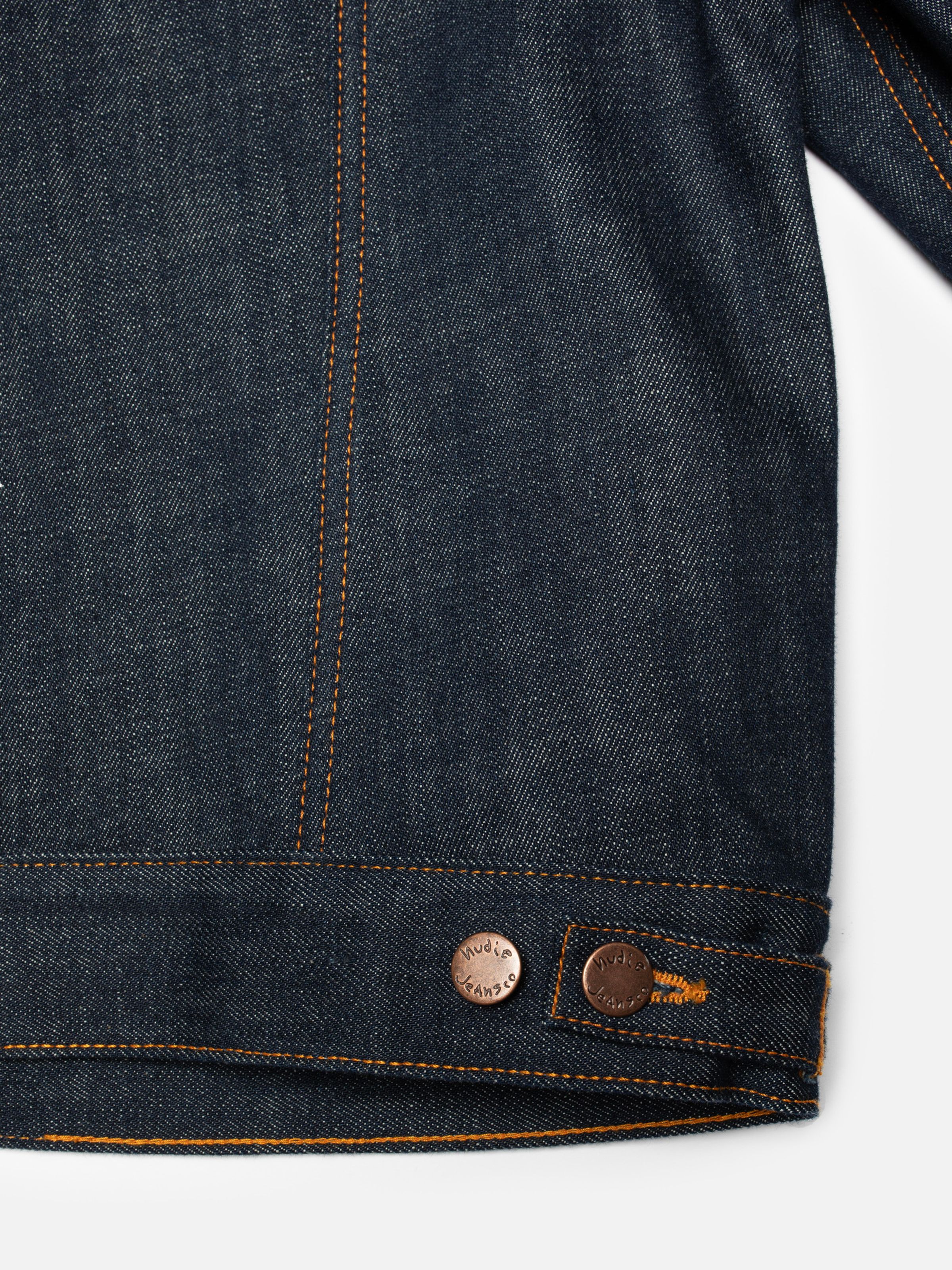 Nudie Jeans Britta Denim Jacket Dry Streaky, close-up of the women's jacket showing the hem and copper adjuster buttons.