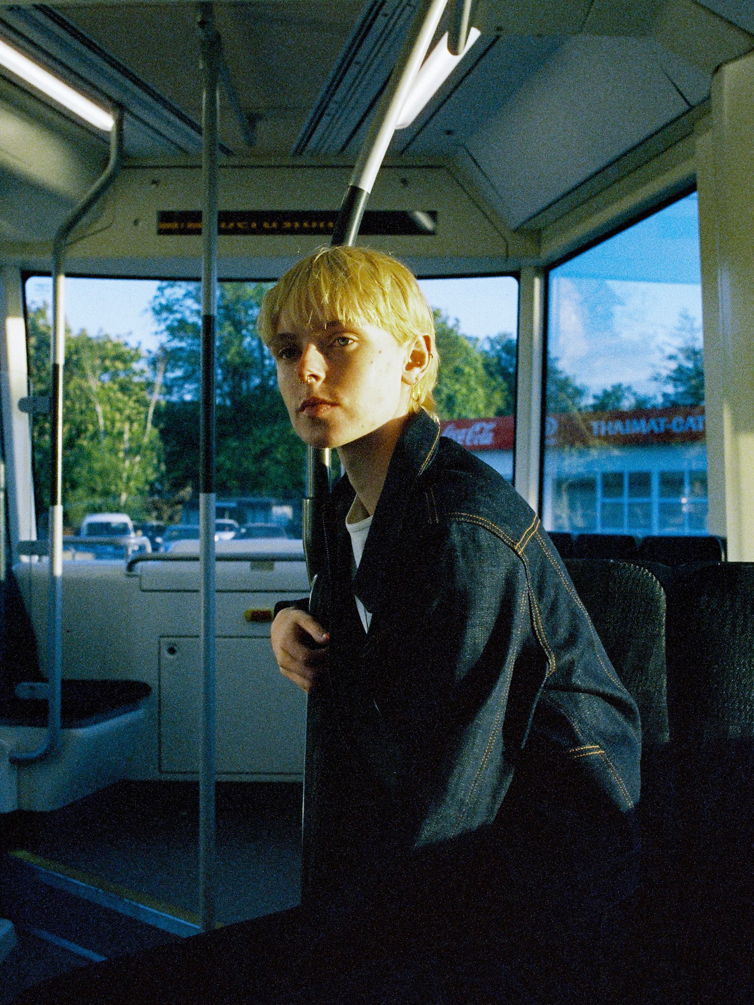 Nudie Jeans Britta Denim Jacket Dry Streaky, women's slim fit denim jacket shown on a model sitting inside a bus.