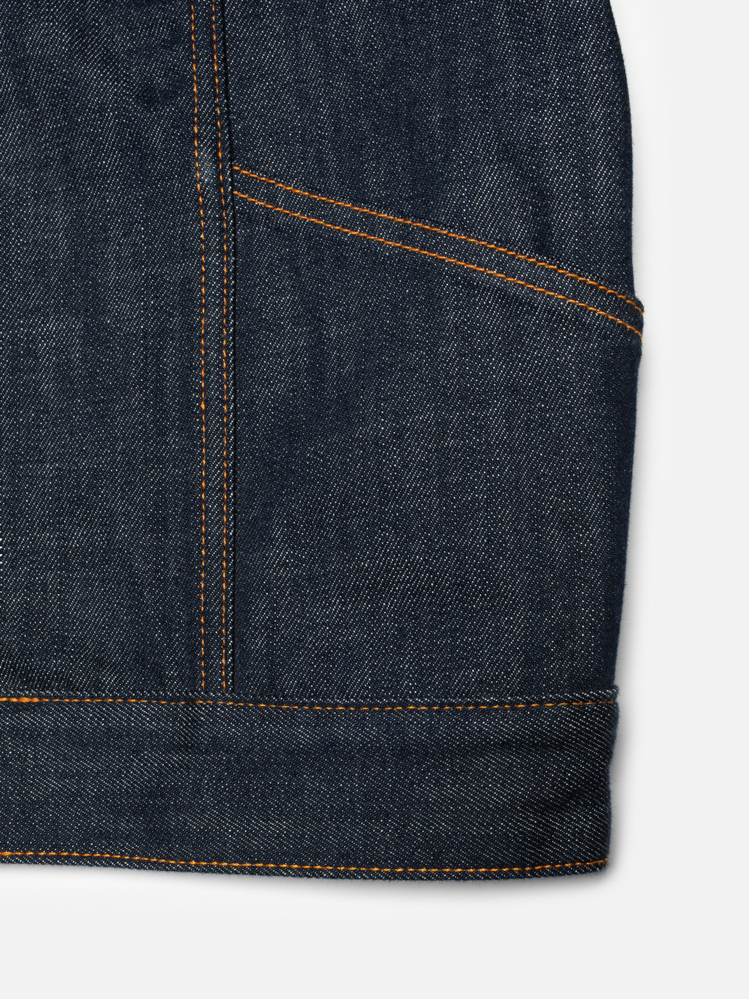 Nudie Jeans Britta Denim Jacket Dry Streaky, close-up of the rigid denim fabric showing the front pocket and hem.