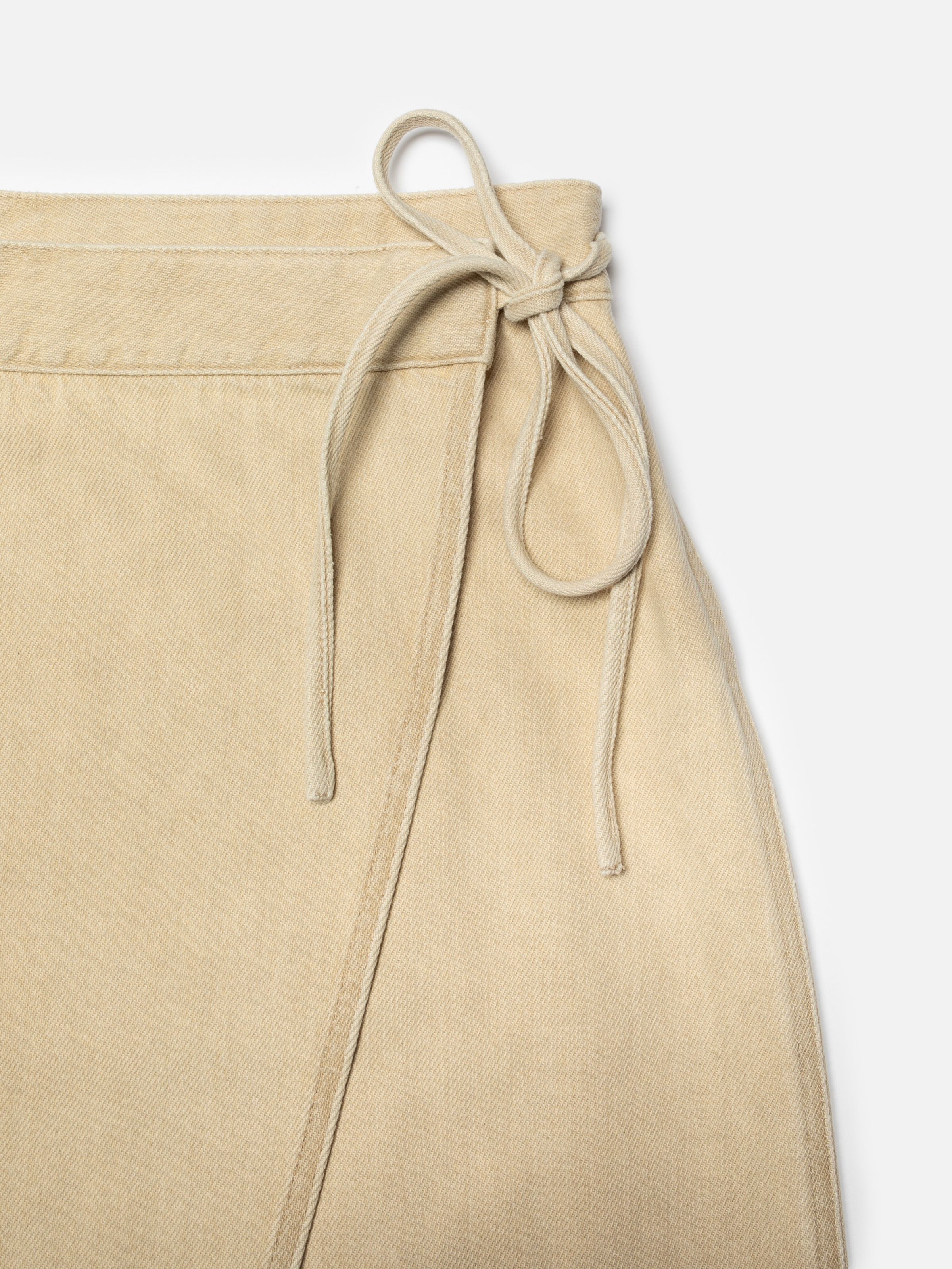 Nudie Jeans Irma Skirt Denim in Pale Yellow, close-up of the wrap design and tie detail at the waistband.