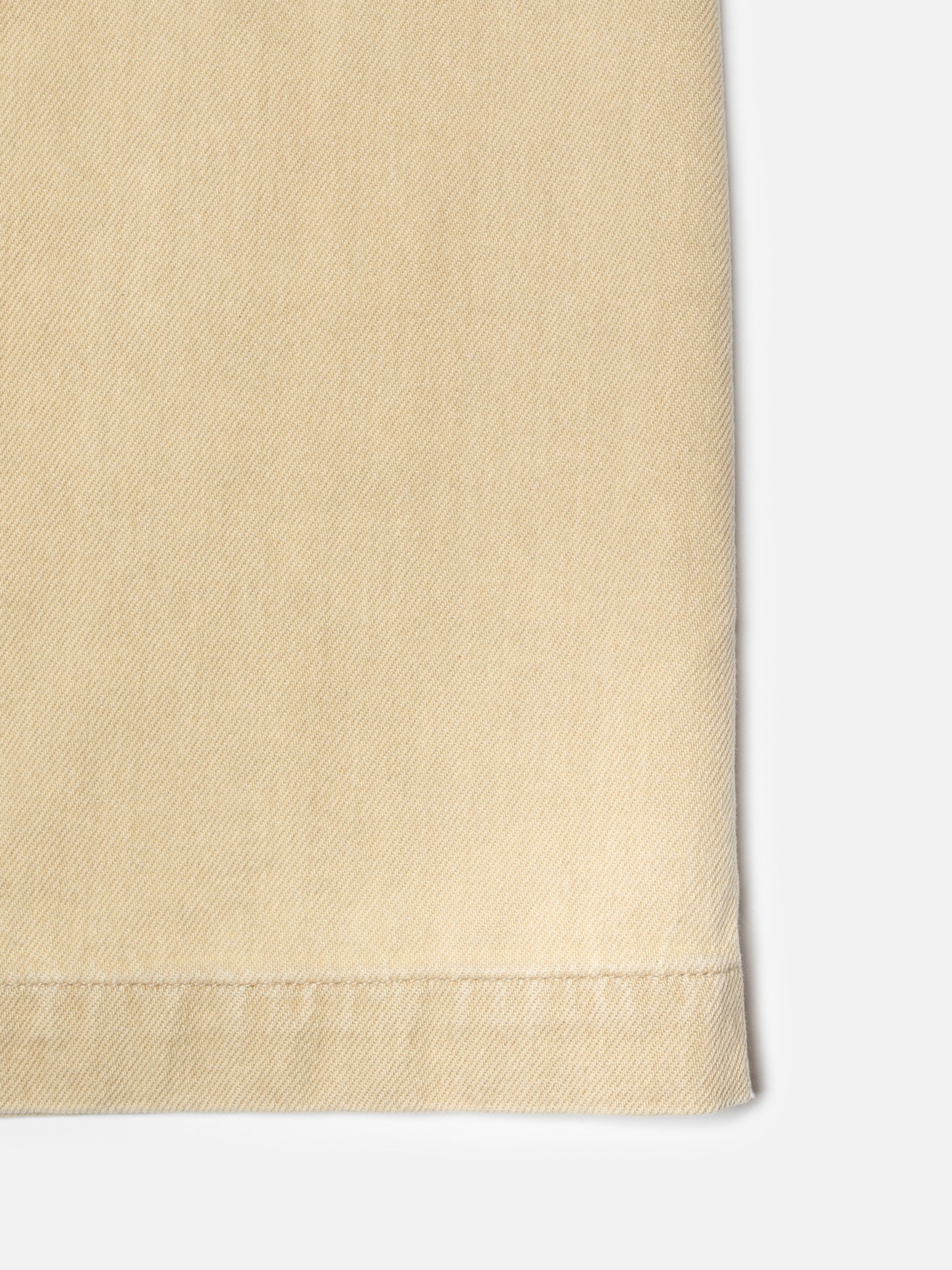 Nudie Jeans Irma Skirt Denim in Pale Yellow, close-up of the rigid denim fabric and hem detail.