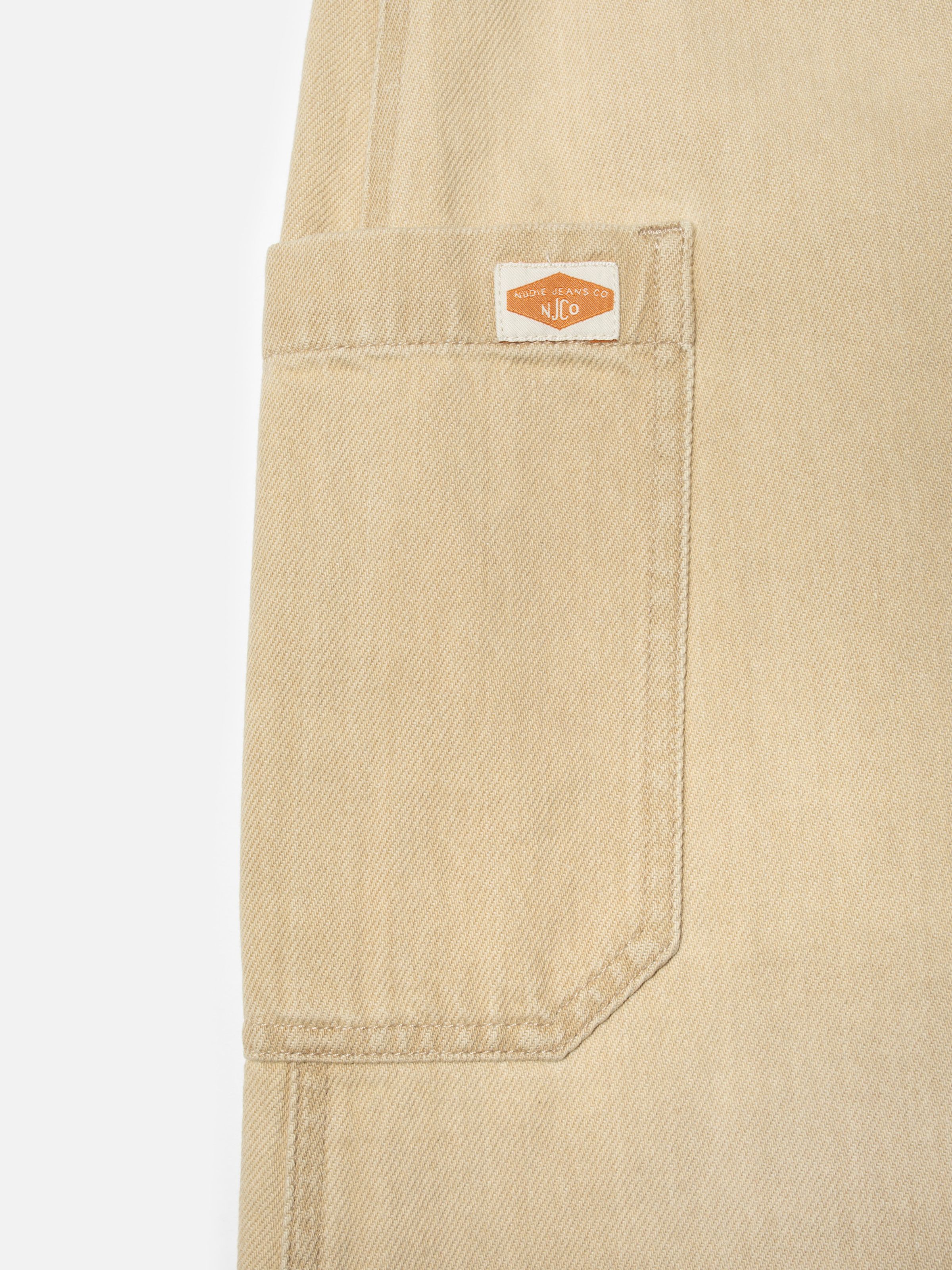 Nudie Jeans Irma Skirt Denim in Pale Yellow, close-up of the rectangular side pocket with the Nudie Jeans Co logo patch.
